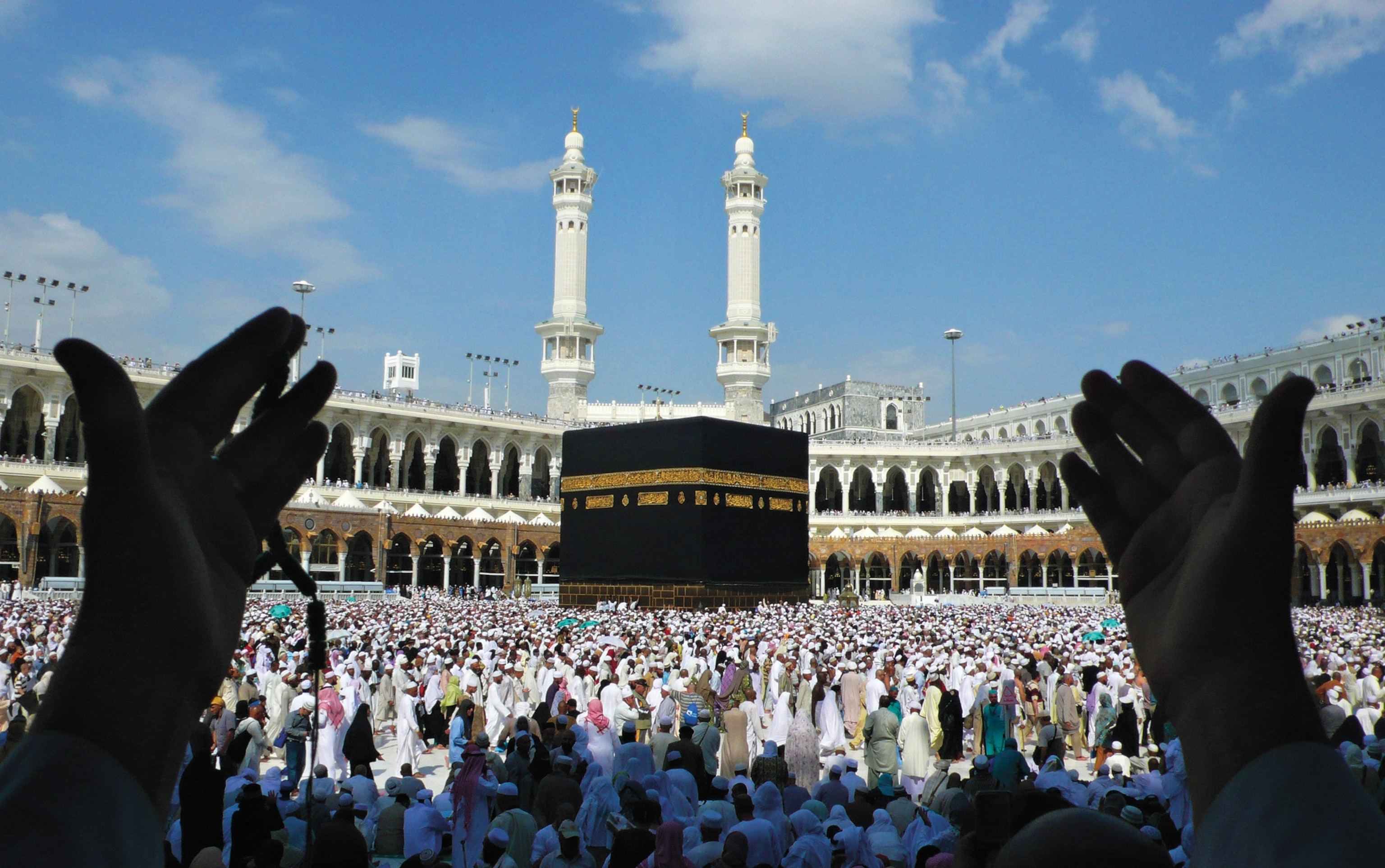 Photo of hands in foreground with many worshippers in front