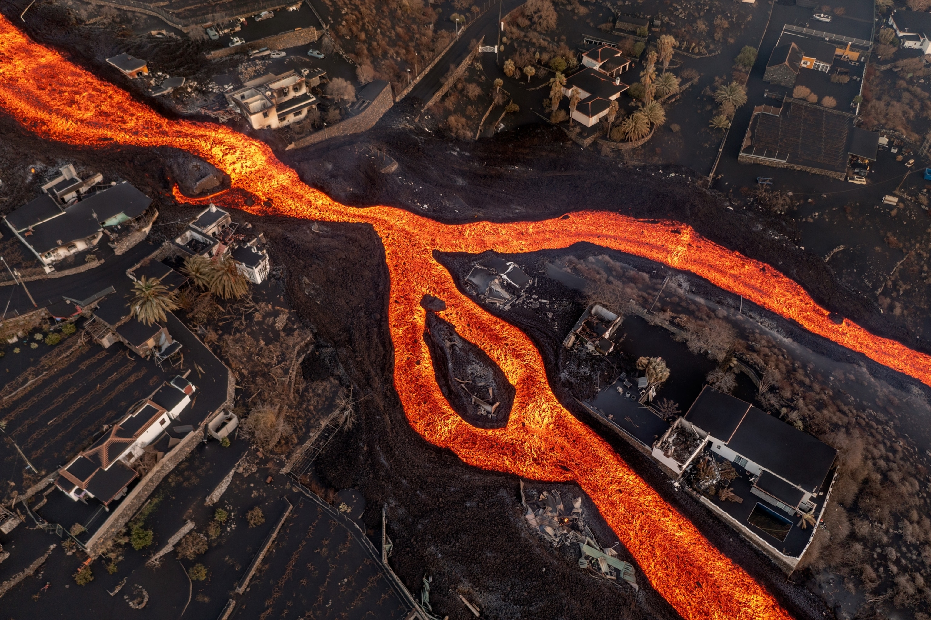 Picture of river of lava streaming between homes.