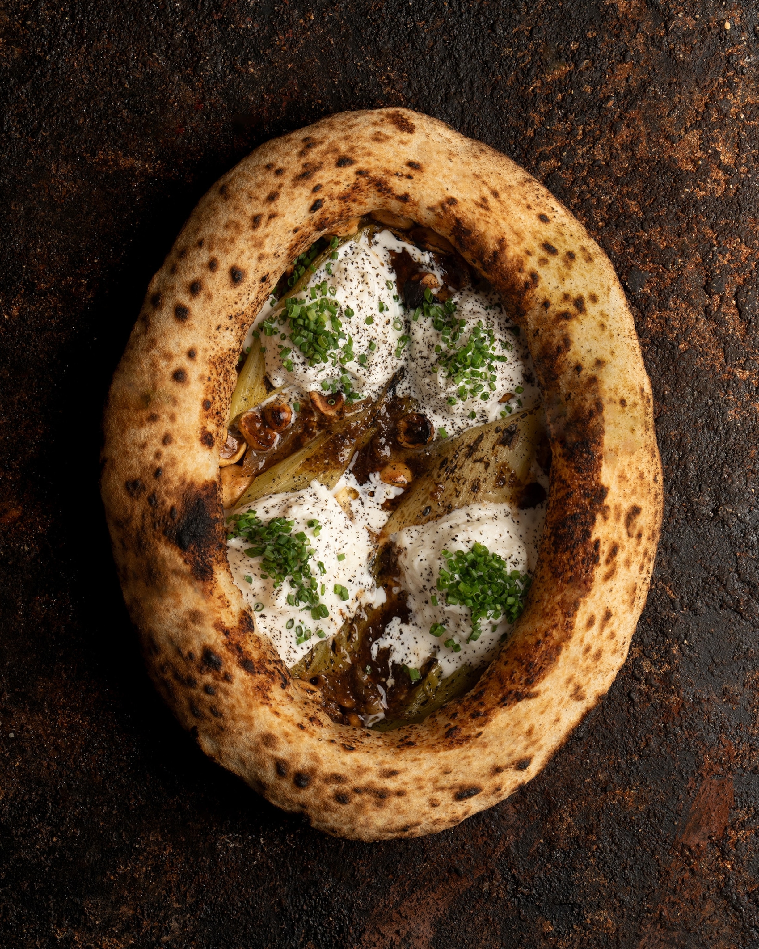Orfali Bros's Burnt Leeks & Truffle with sourdough, brown butter miso, hazelnuts, stracciatella, and chives.