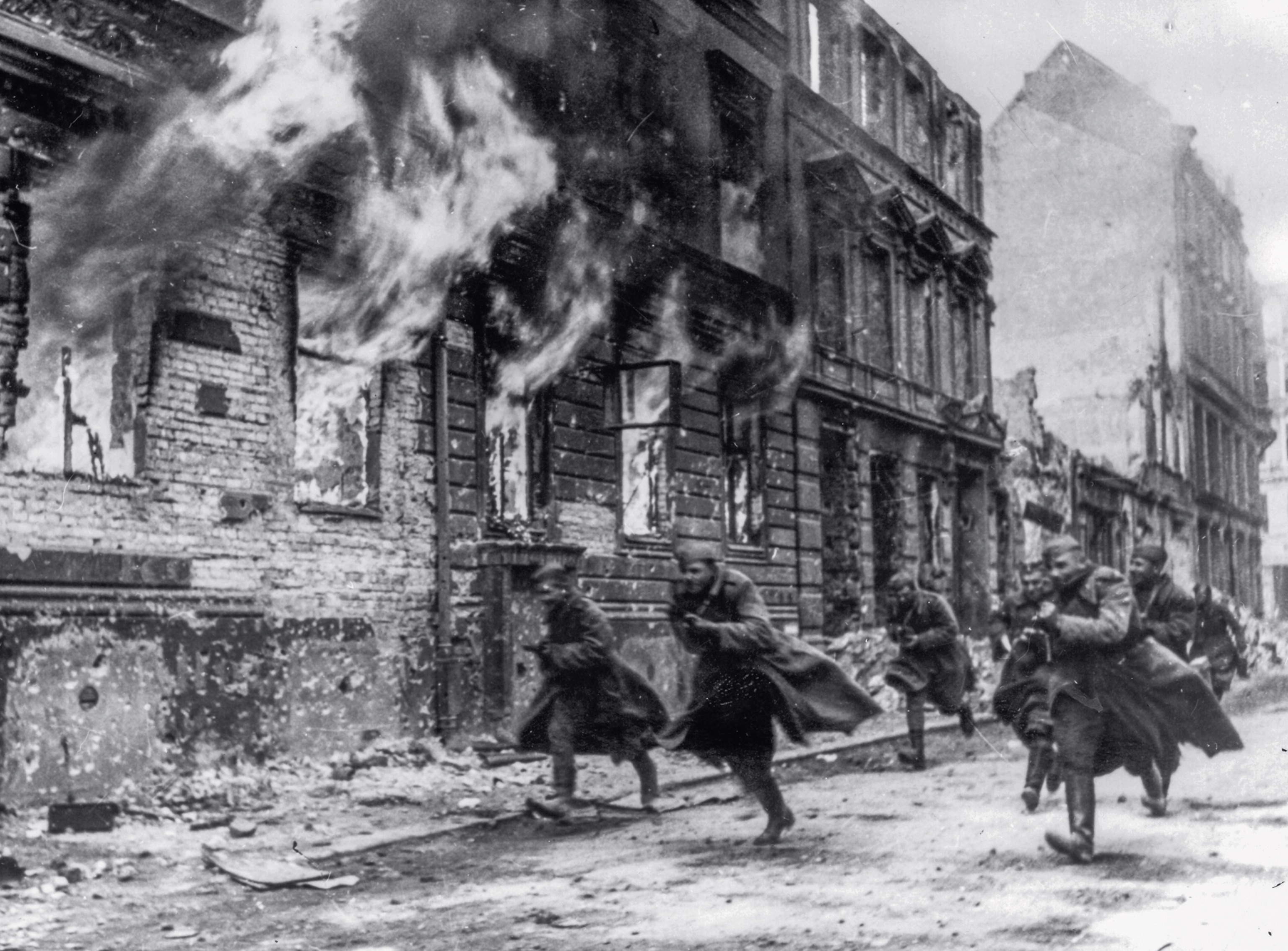 soldiers running in the streets next to a burning building