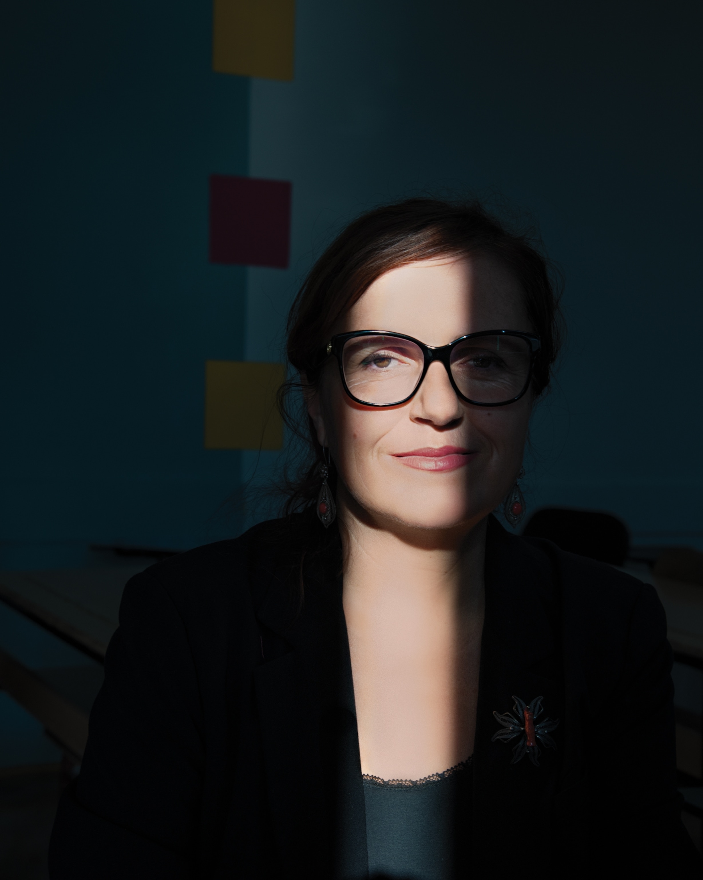 Picture of a woman wearing dark clothes with a streak of light shinning vertically on her face.