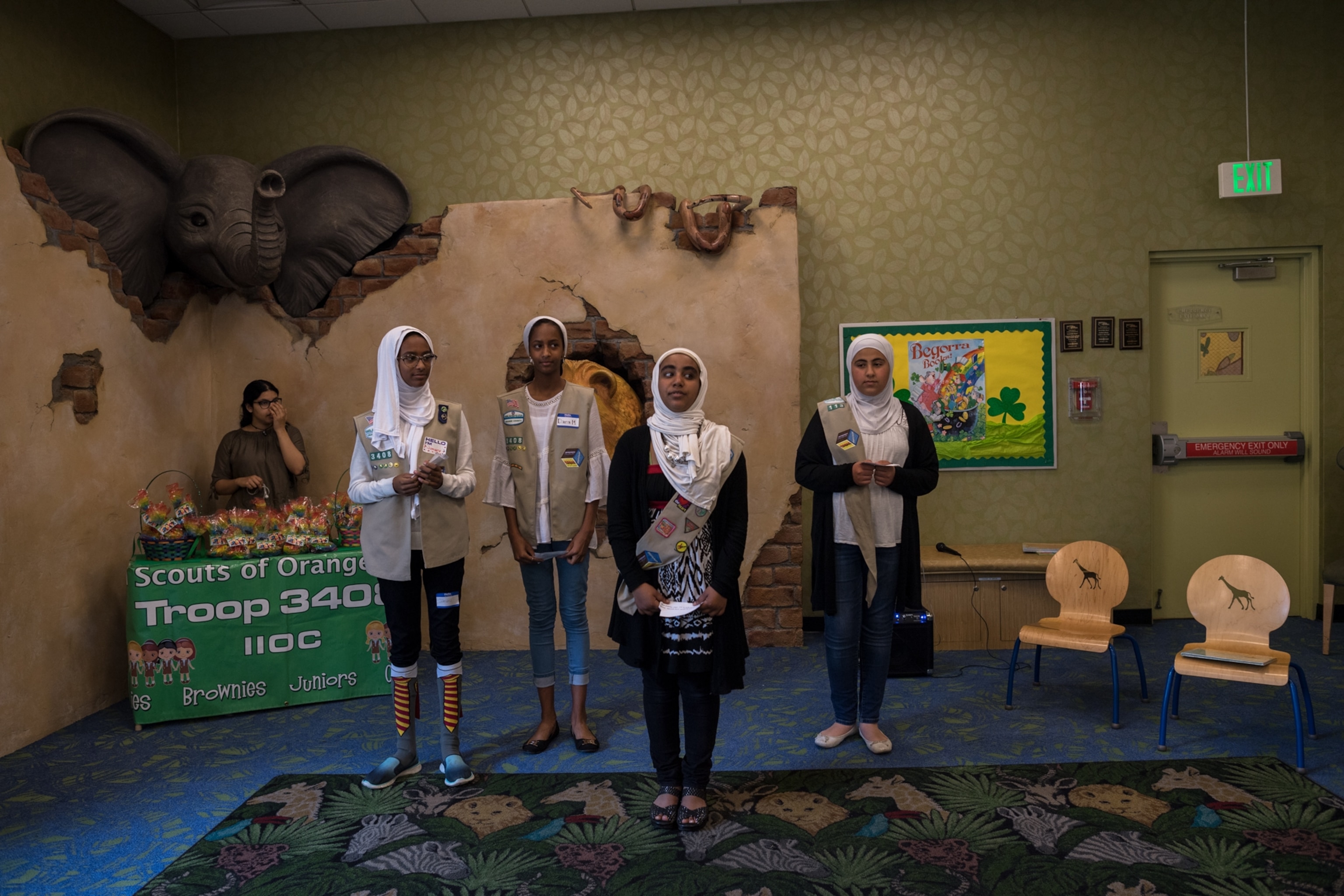 hijabi girl scouts wearing their vests and standing inside during their troop meeting