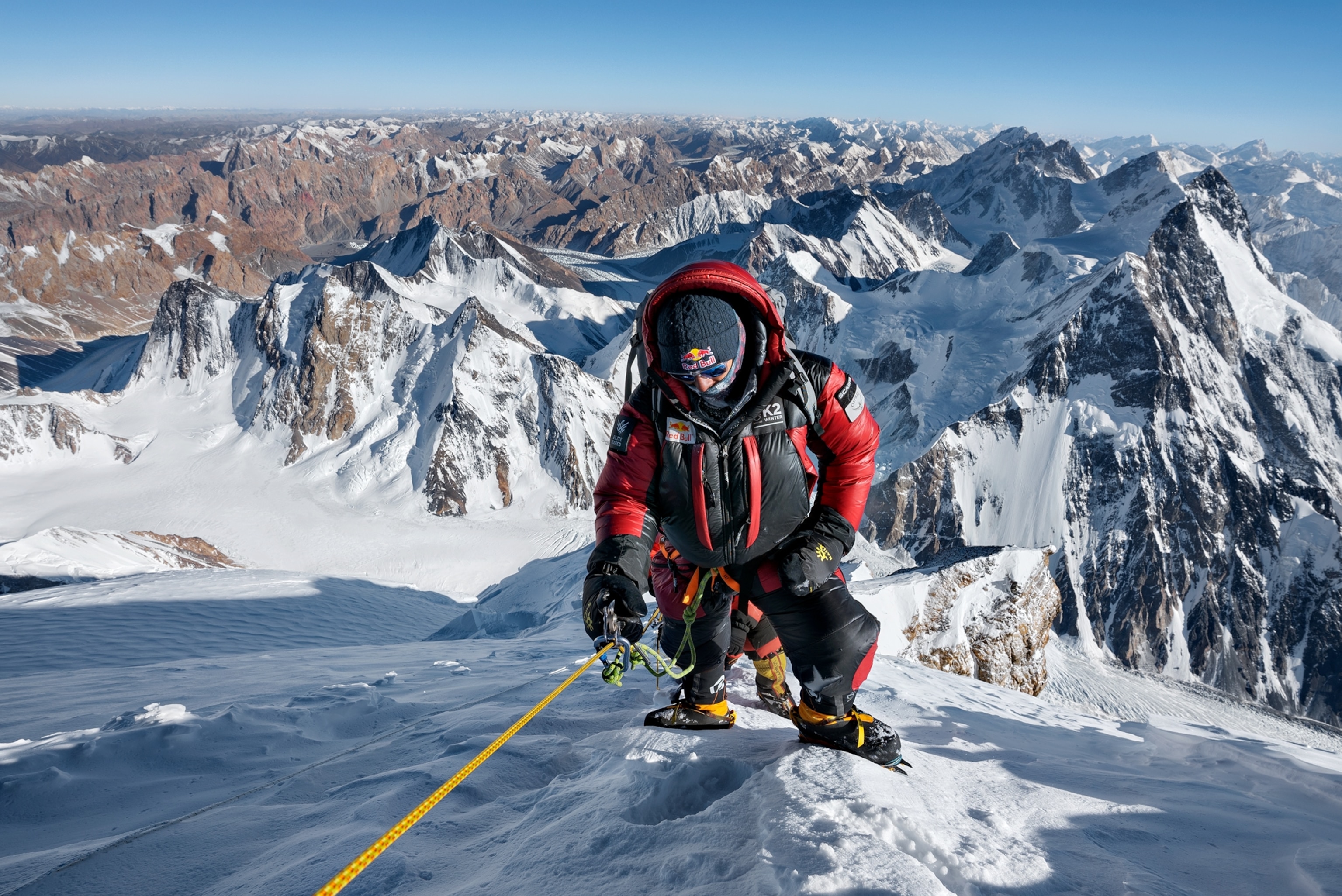 Picture of man in heavy winter climbing gears pulling up on the rope.