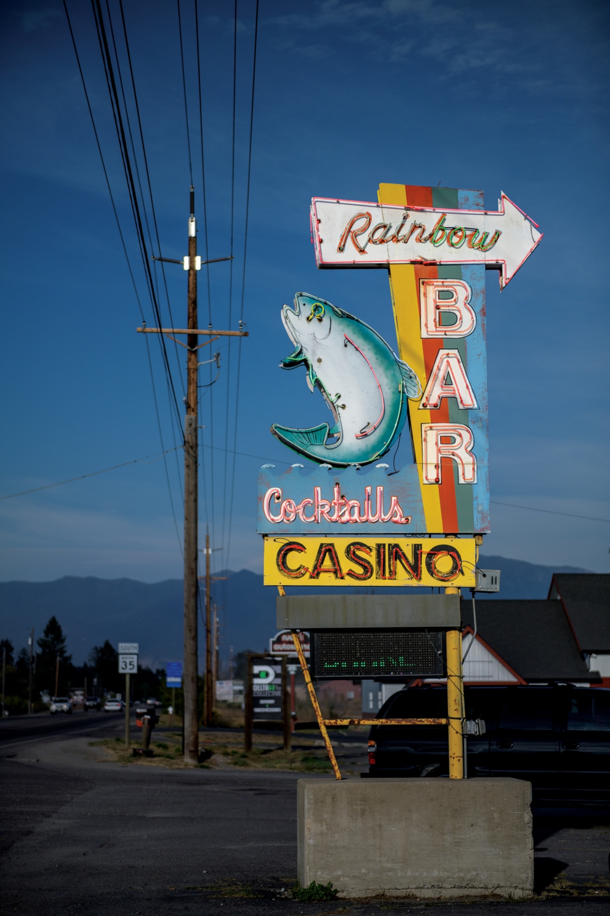 Picture of a neon sign for a bar and casino, decorated with a rainbow trout.