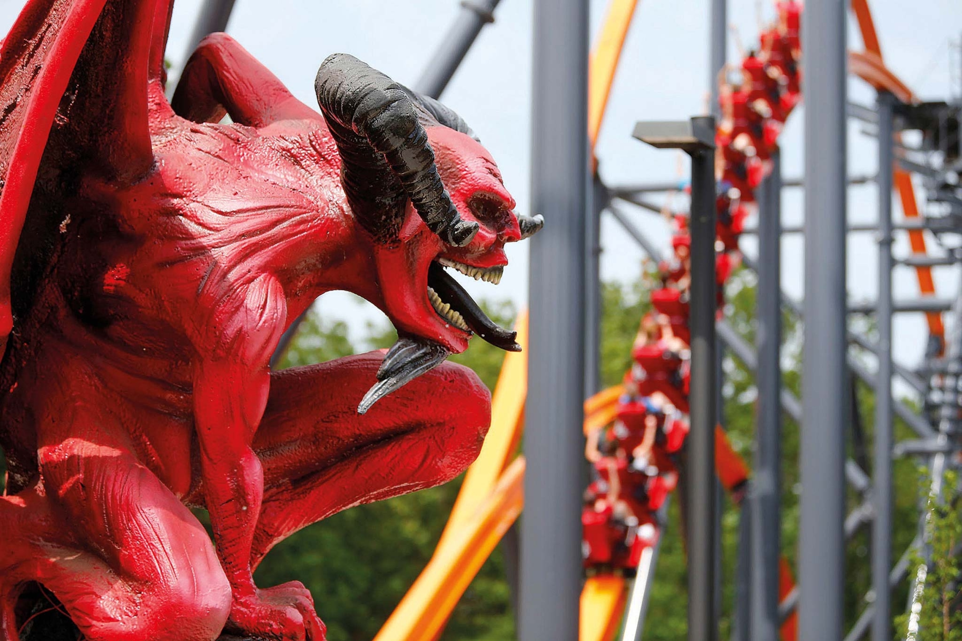 The Jersey Devil Coaster's red devil statue sits in the foreground with the rollercoaster dropping in the background