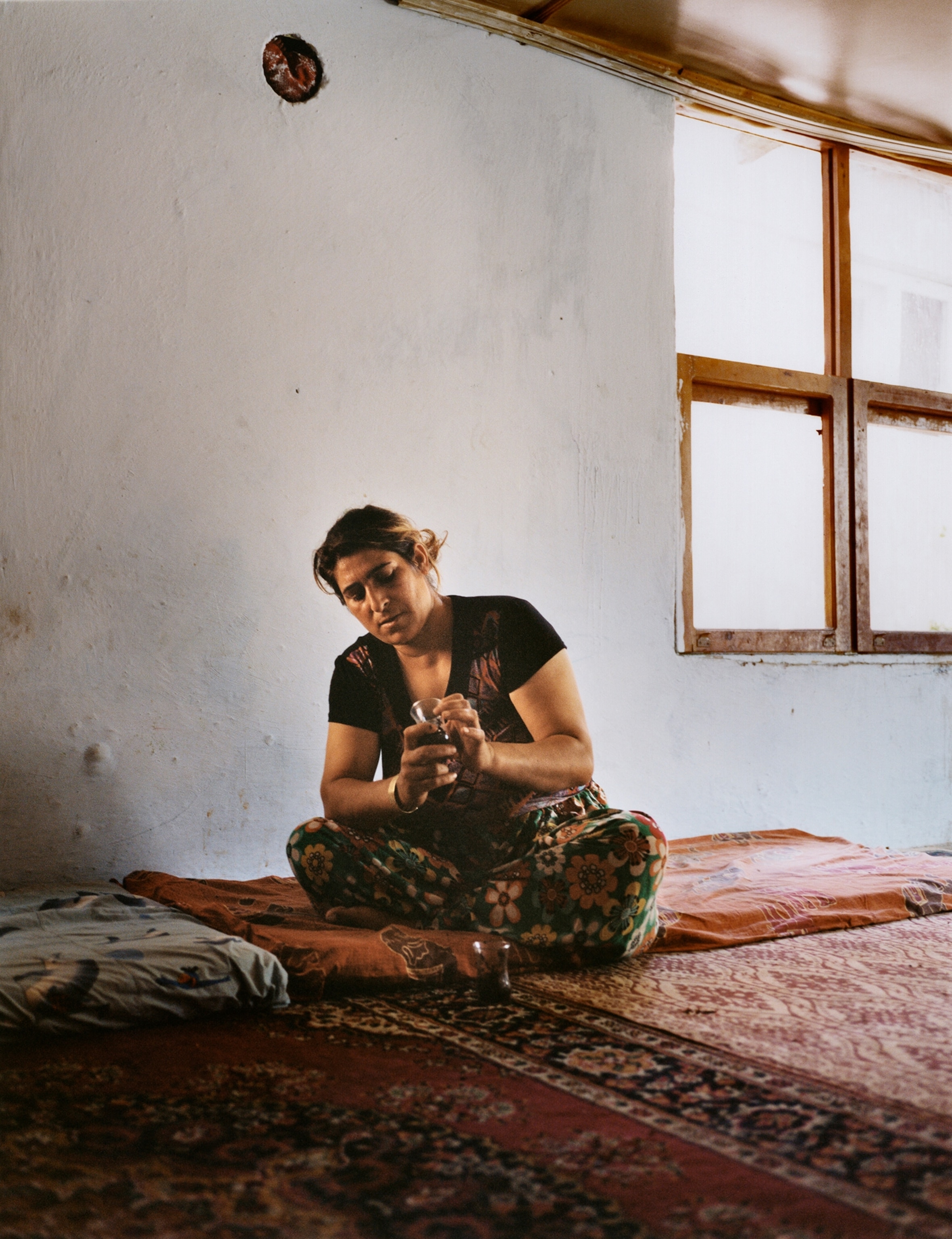A woman sits down legs crossed looking intently at tea leaves.