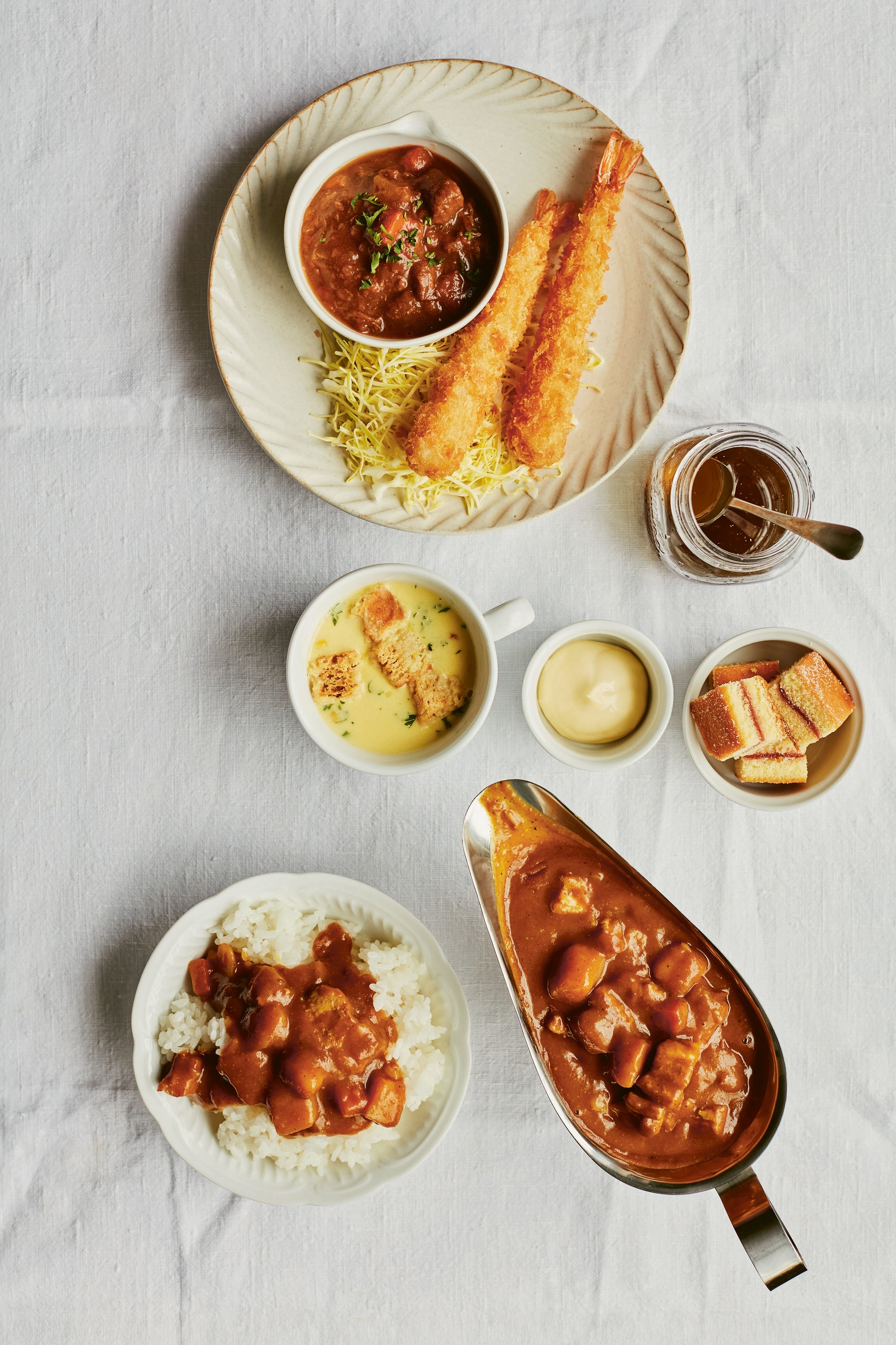 A selection of different dishes including fried crab croquettes, rice, curry and soup.