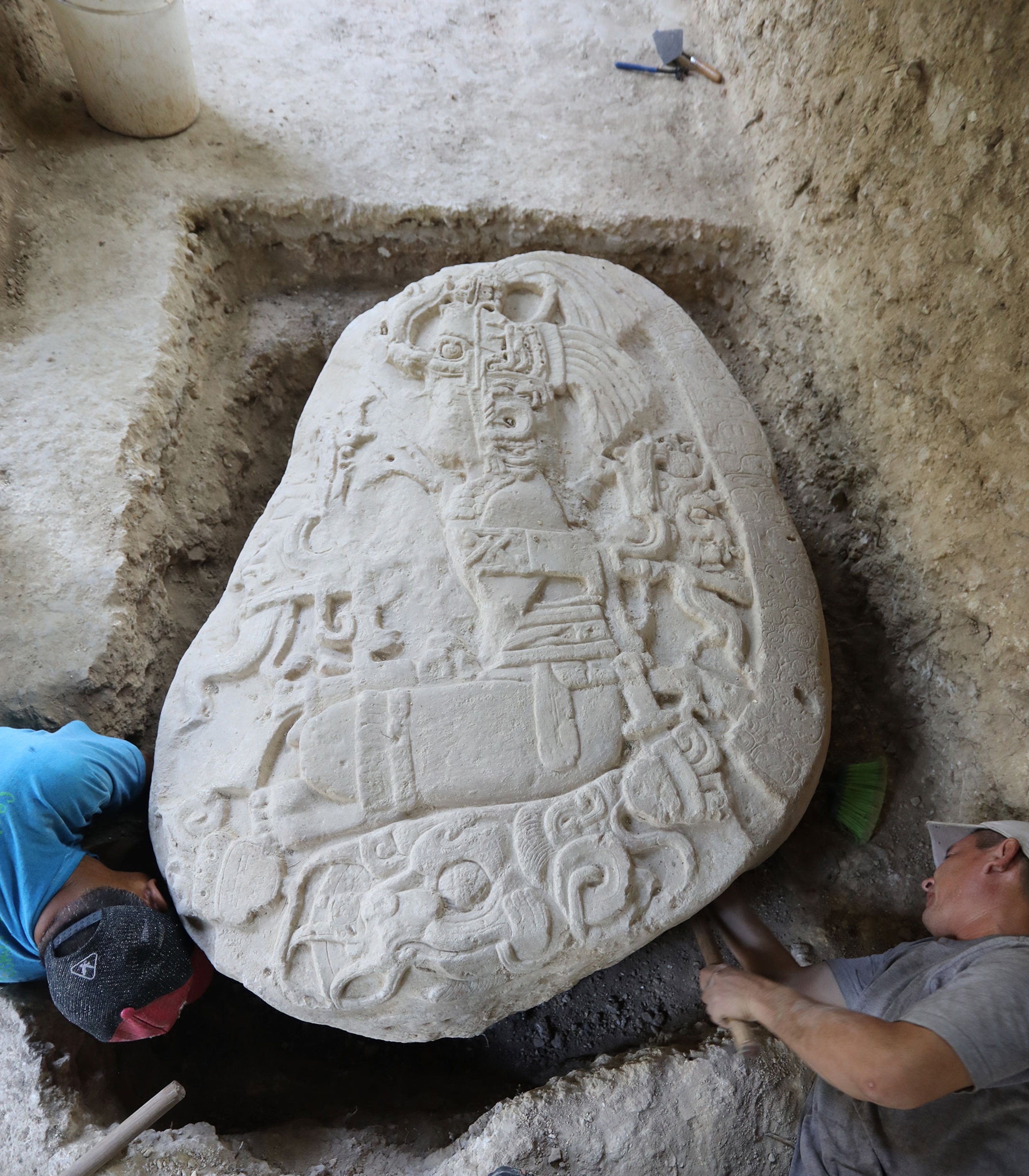 Archeologists remove dig out a large engraved stone