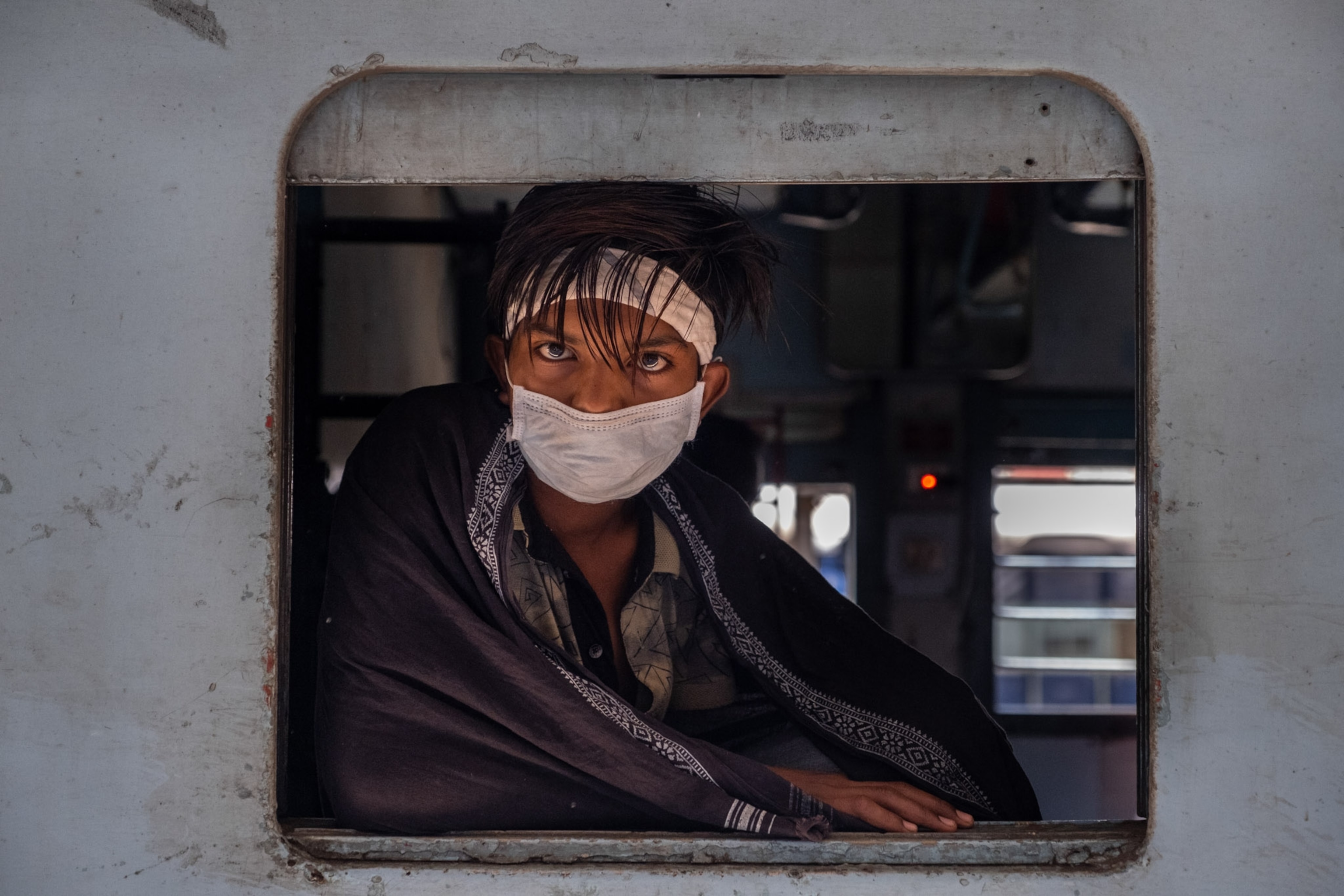 a person looking through a window opening, wearing a mask