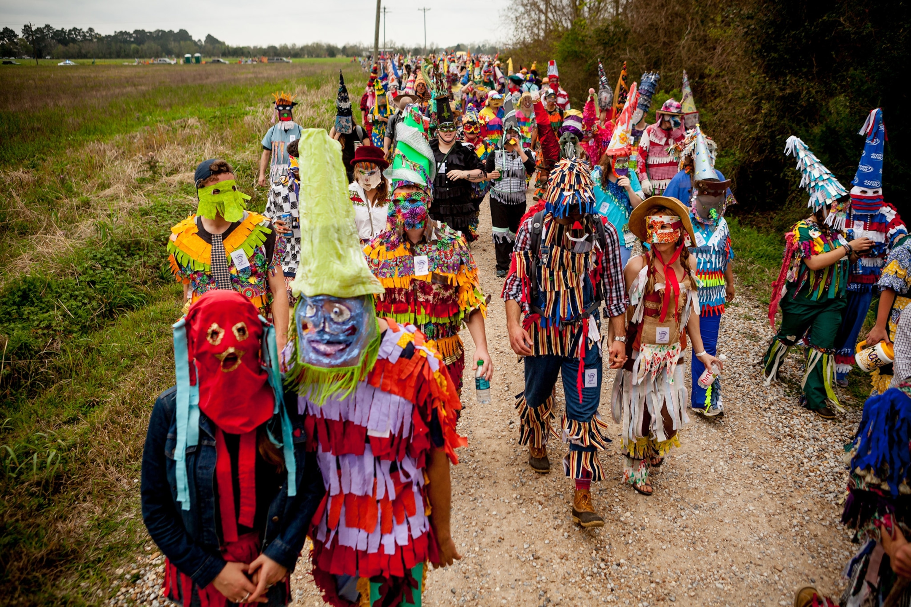 people walking through the countryside at the Courir de Mardi Gras celebration