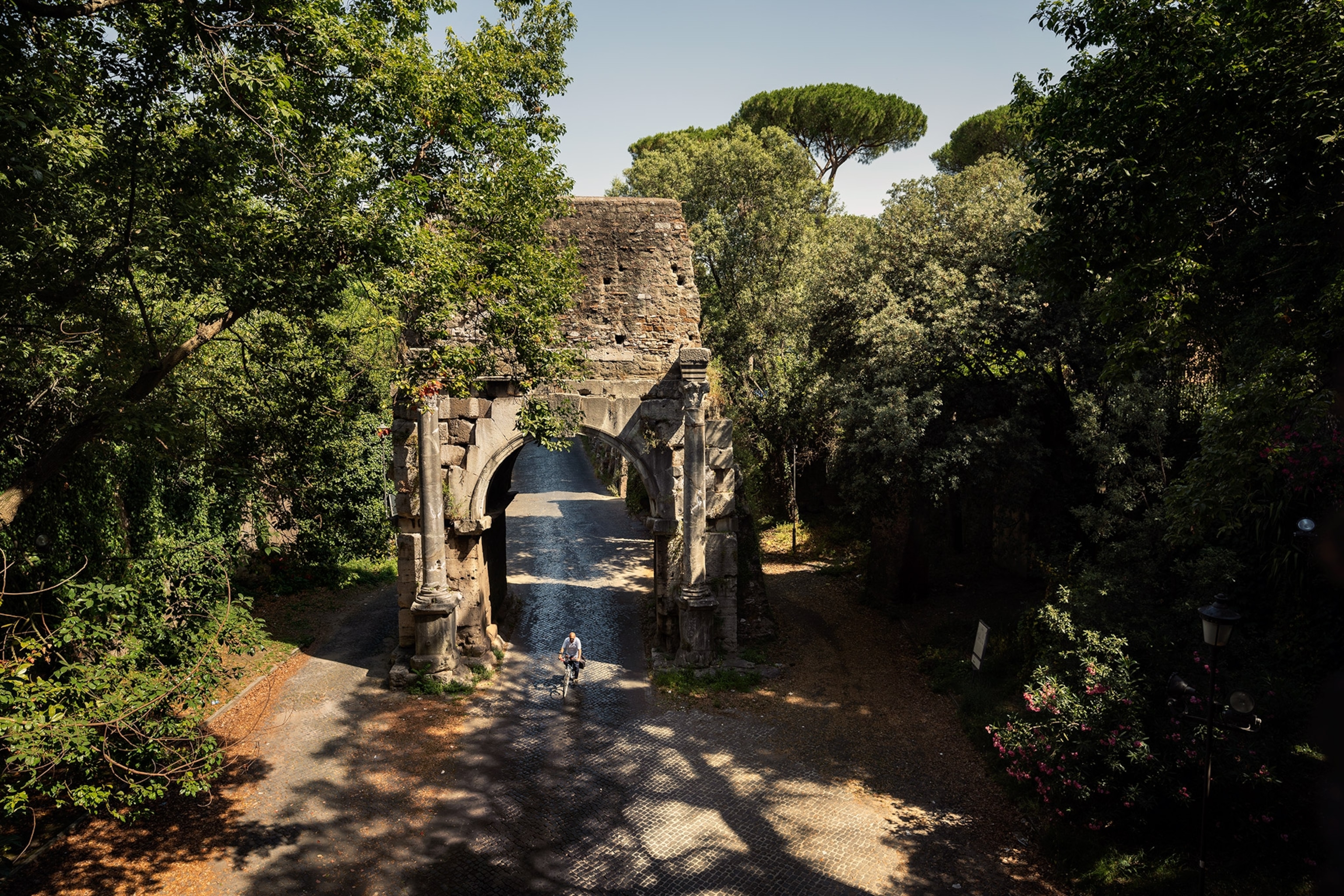 A person rides a bike through Rome’s third-century Arch of Drusus, which marks the start of a planned 360-mile walking route along the Appian Way
