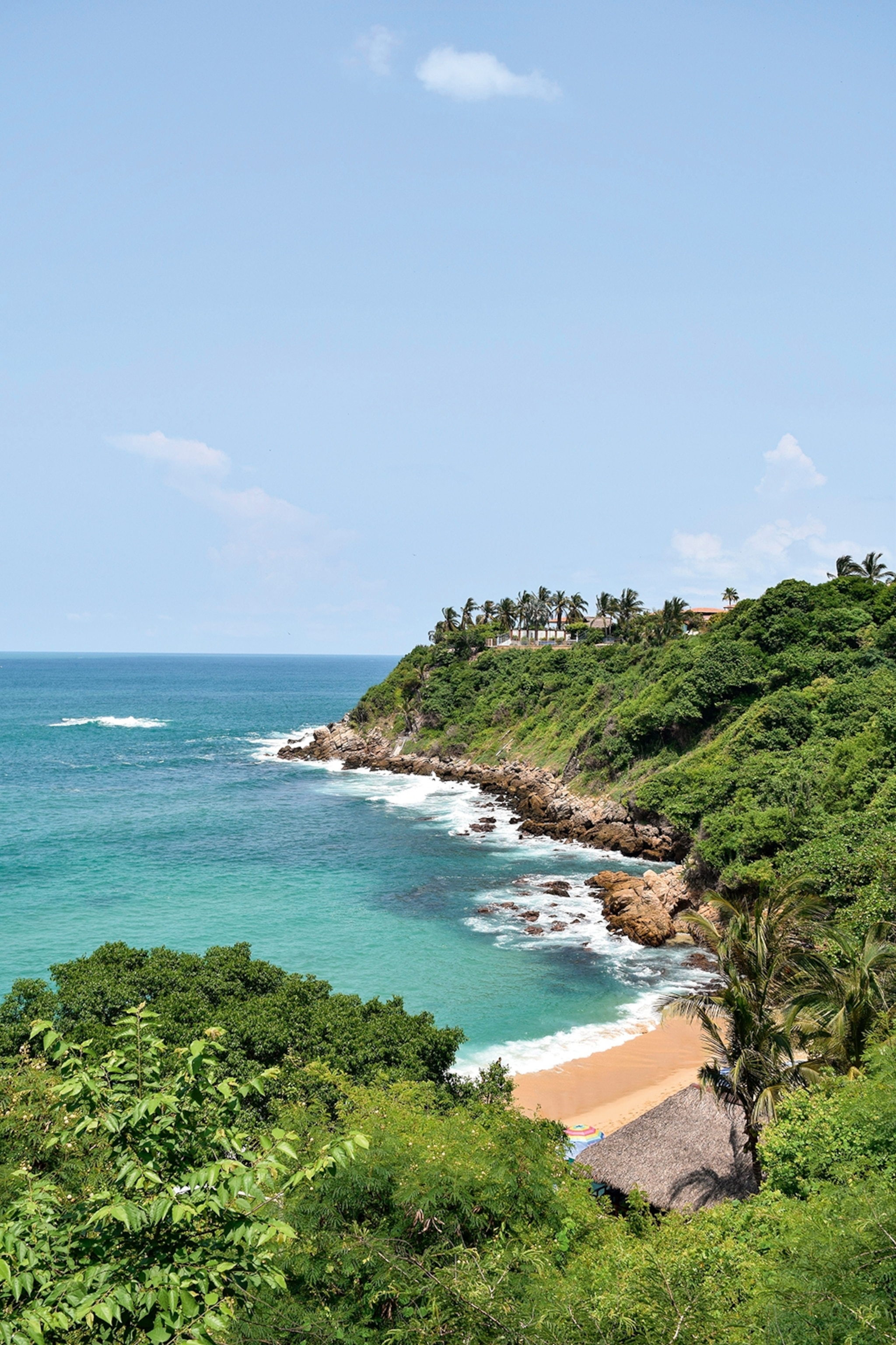 A view onto a a small bay beach surrounded by vibrant vegetation.