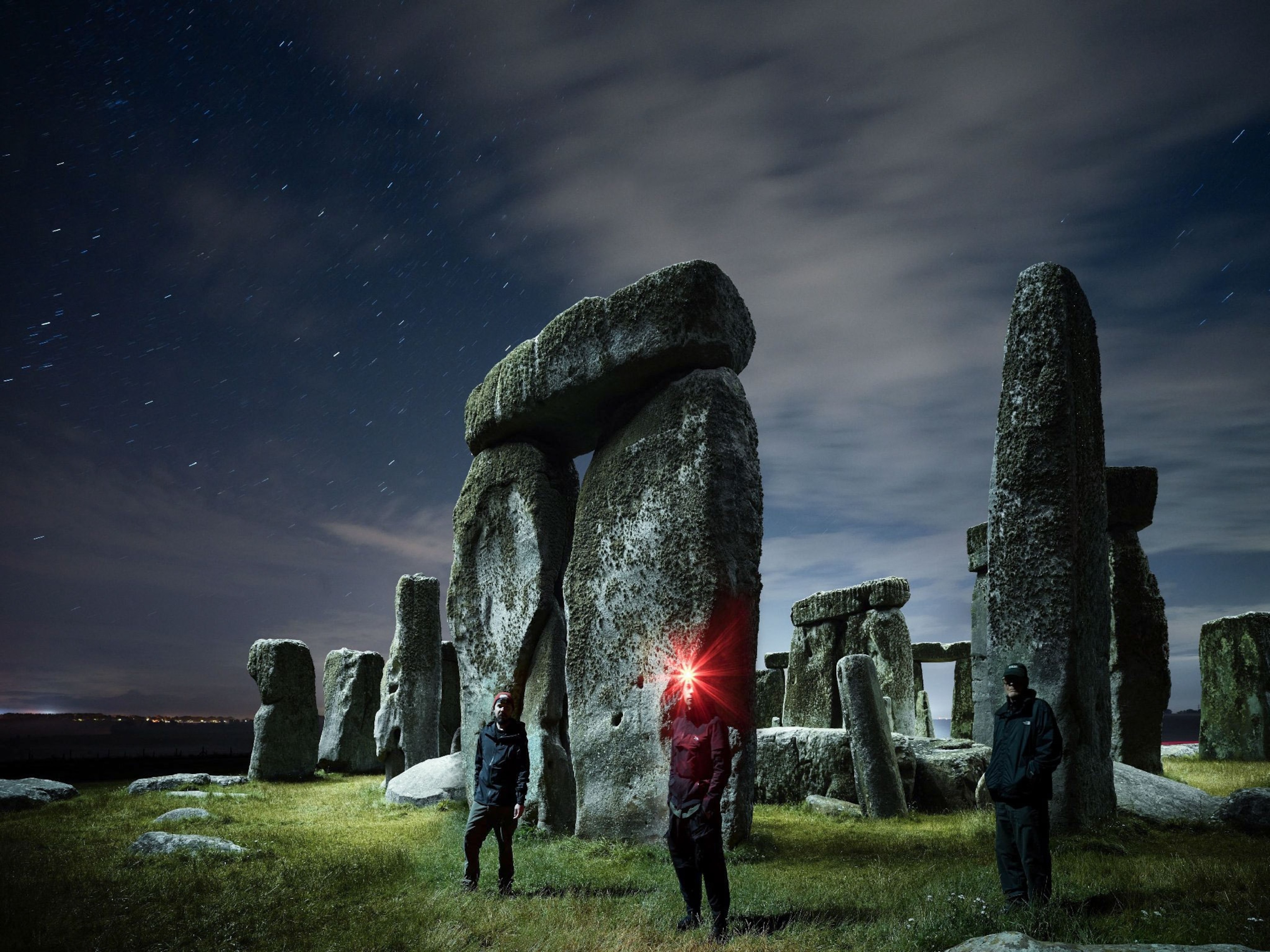 a self portrait of two photographers and a security guard in front of Stonehenge at night