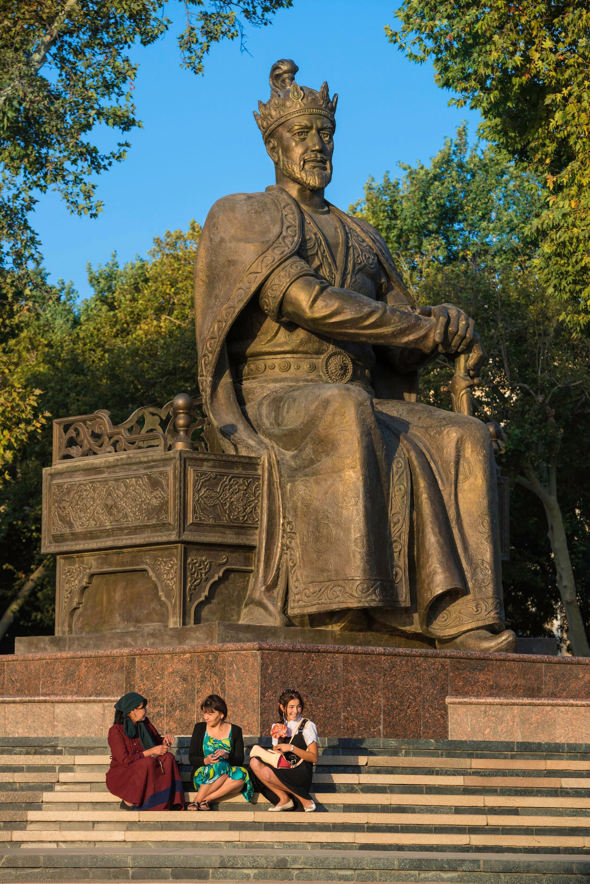 People sit at the bottom of a Timur statue