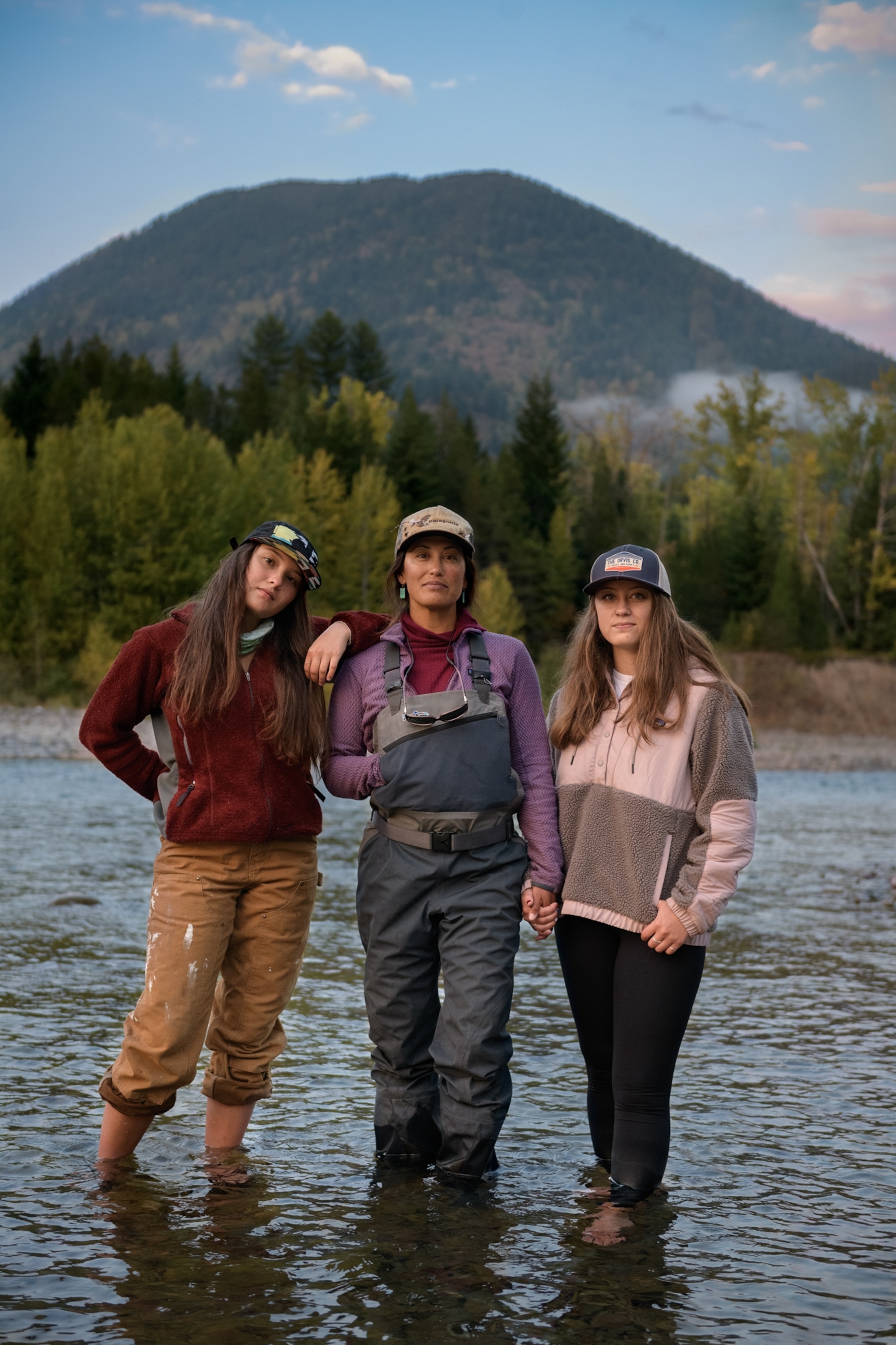 Picture of Hilary Hutcheson wearing waders, standing in the Flathead River with her daughters at her side.