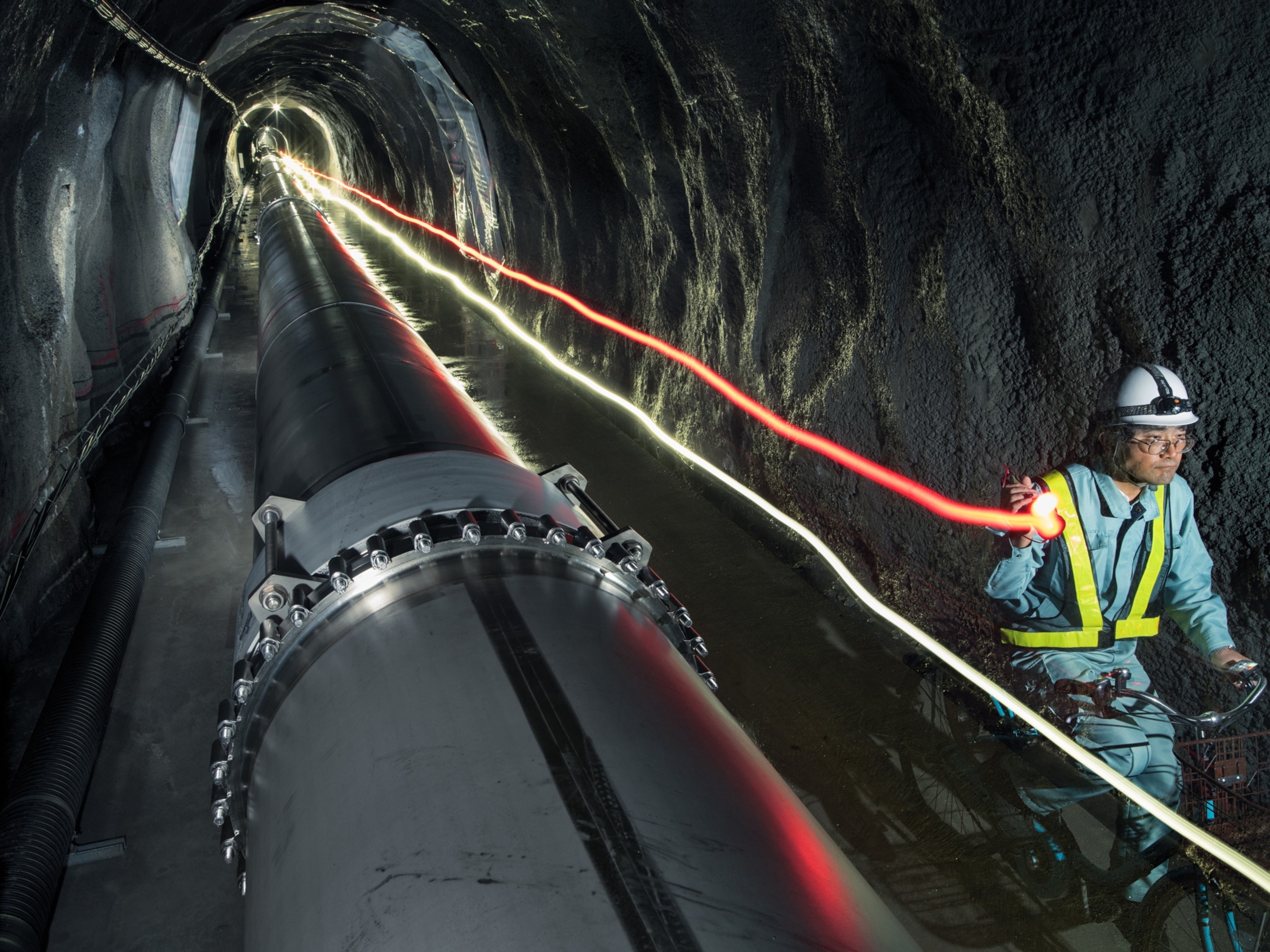 scientist on bicycle riding along underground gravitational wave telescope in Hida, Japan