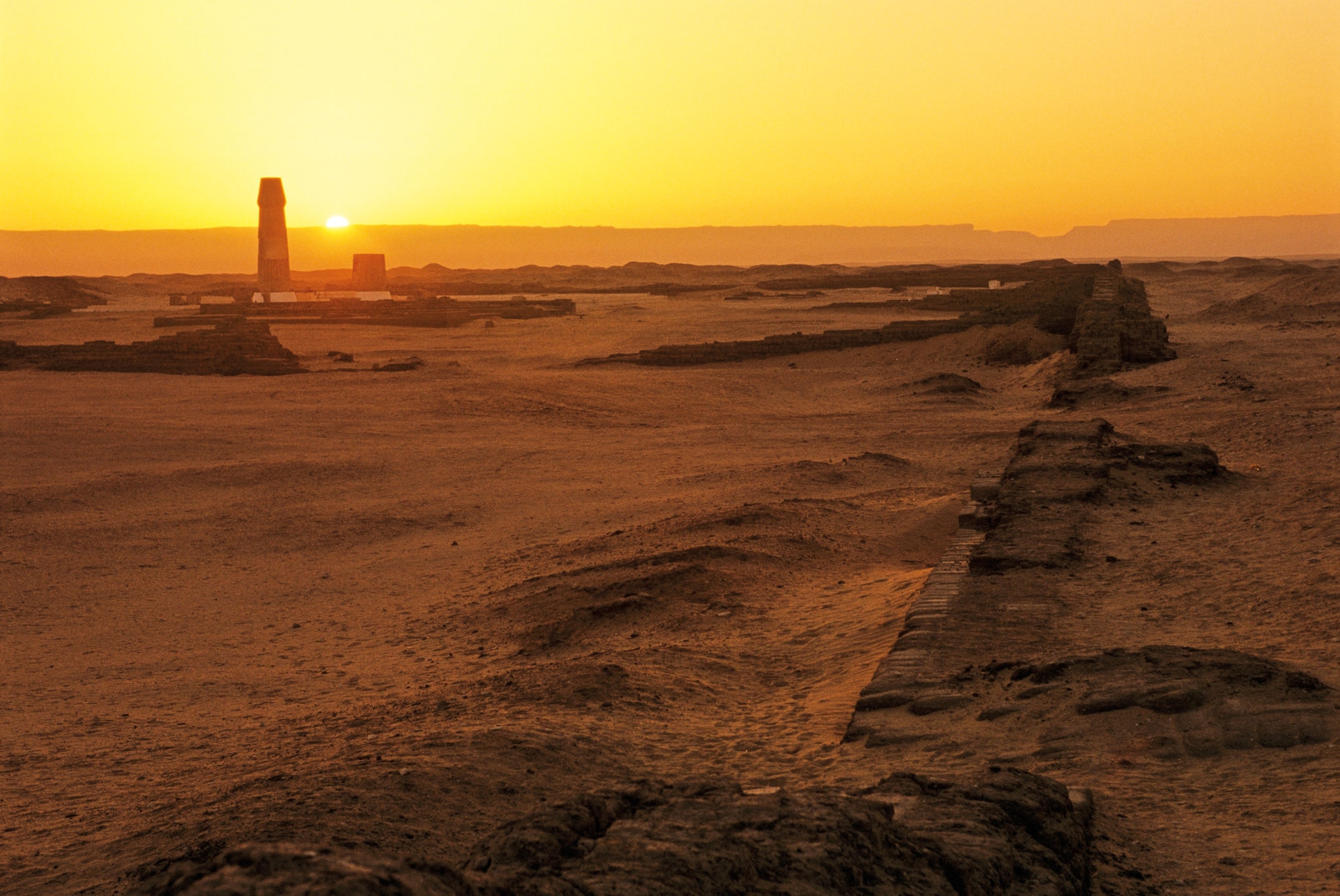 A bright yellow sunset over a dry land