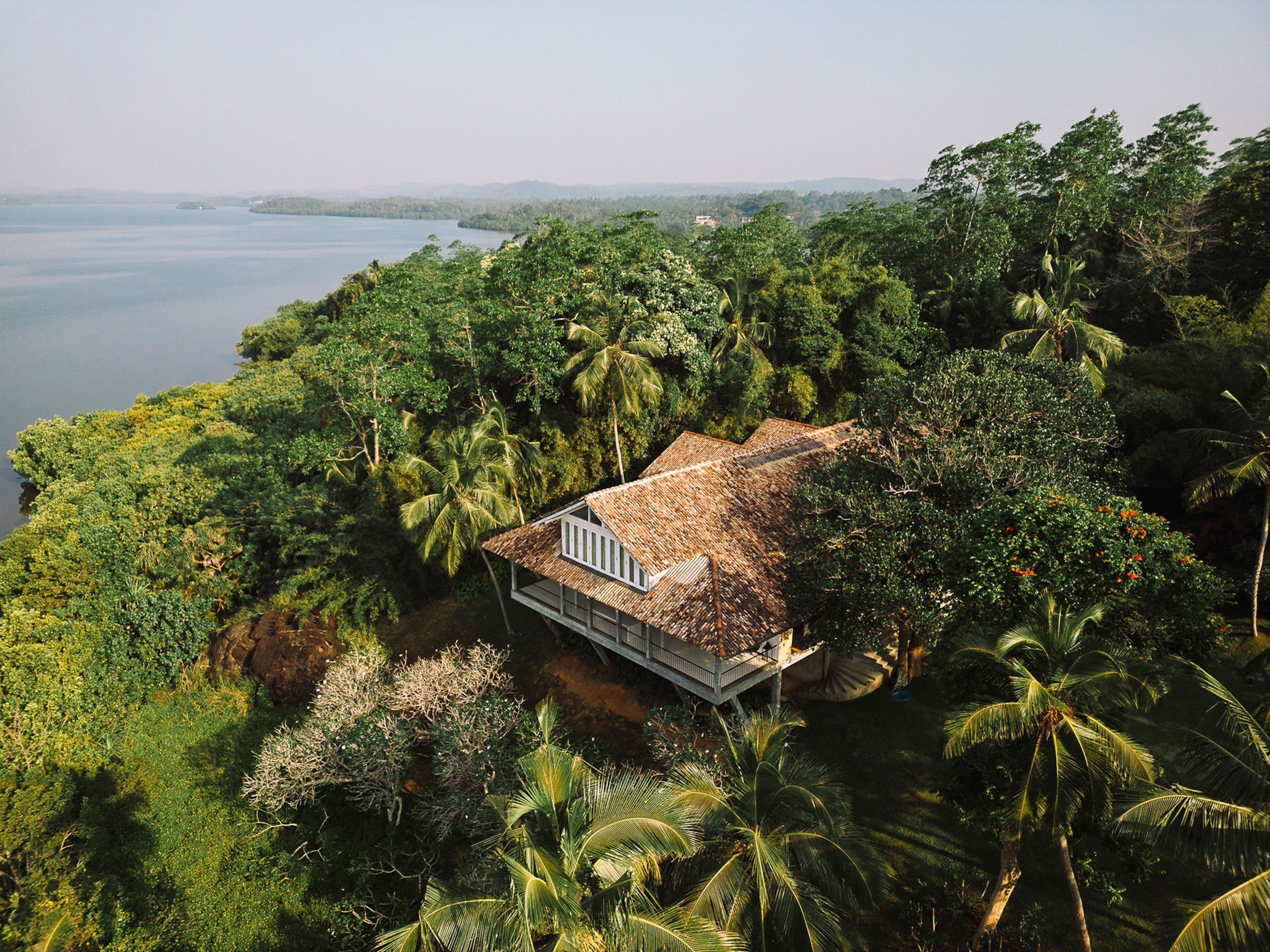 An aerial of the wellness center at Kurulu Bay surrounded by trees and a view of Koggala Lake.
