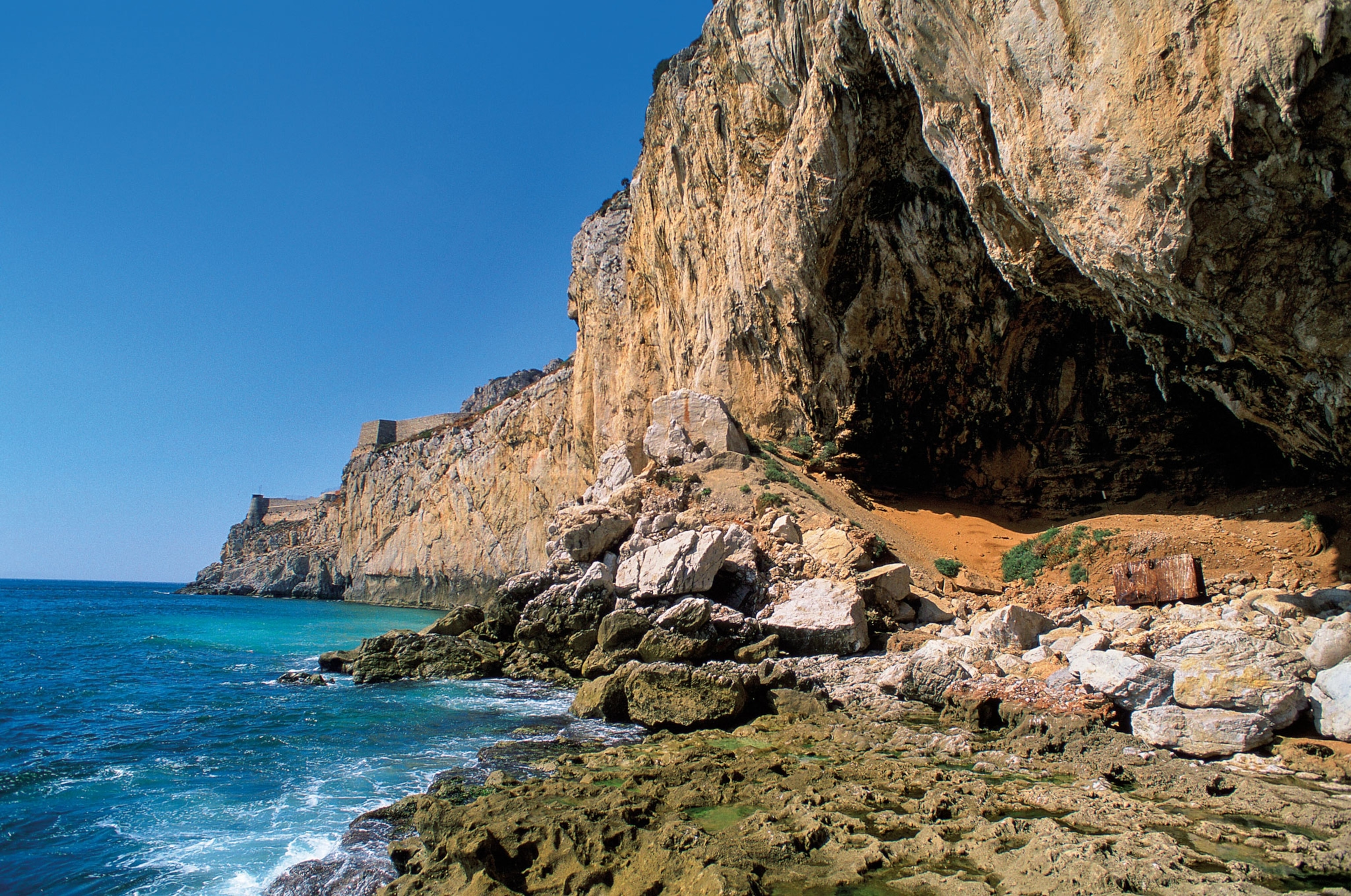 a cliff face and caves along the sea