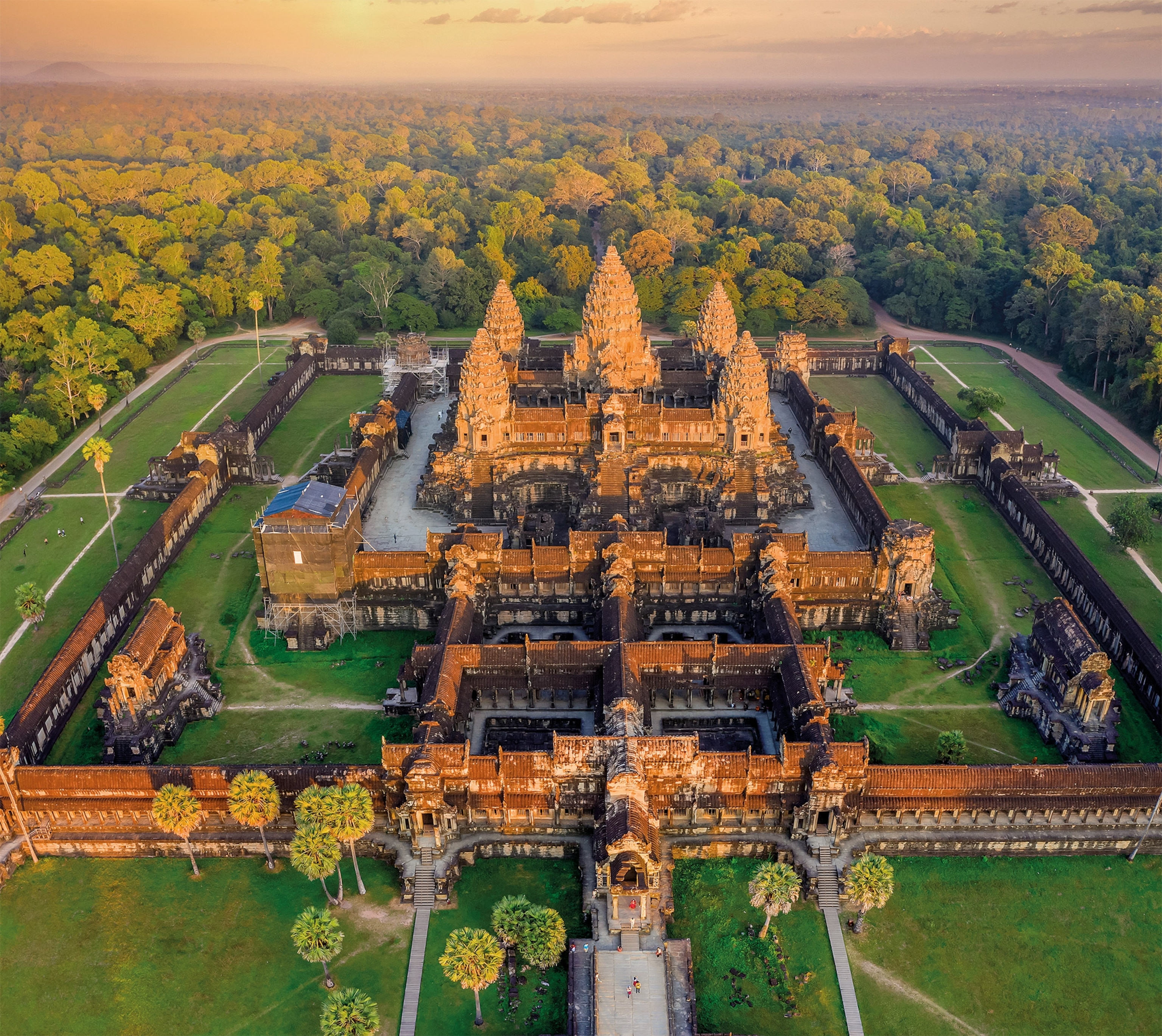 An aerial view of Angkor Wat offers a fresh perspective on the 900-year-old complex, showcasing its intricate shapes and sheer magnitude. A wall nearly 15 feet high surrounds the temple, with an entrance at each cardinal point.