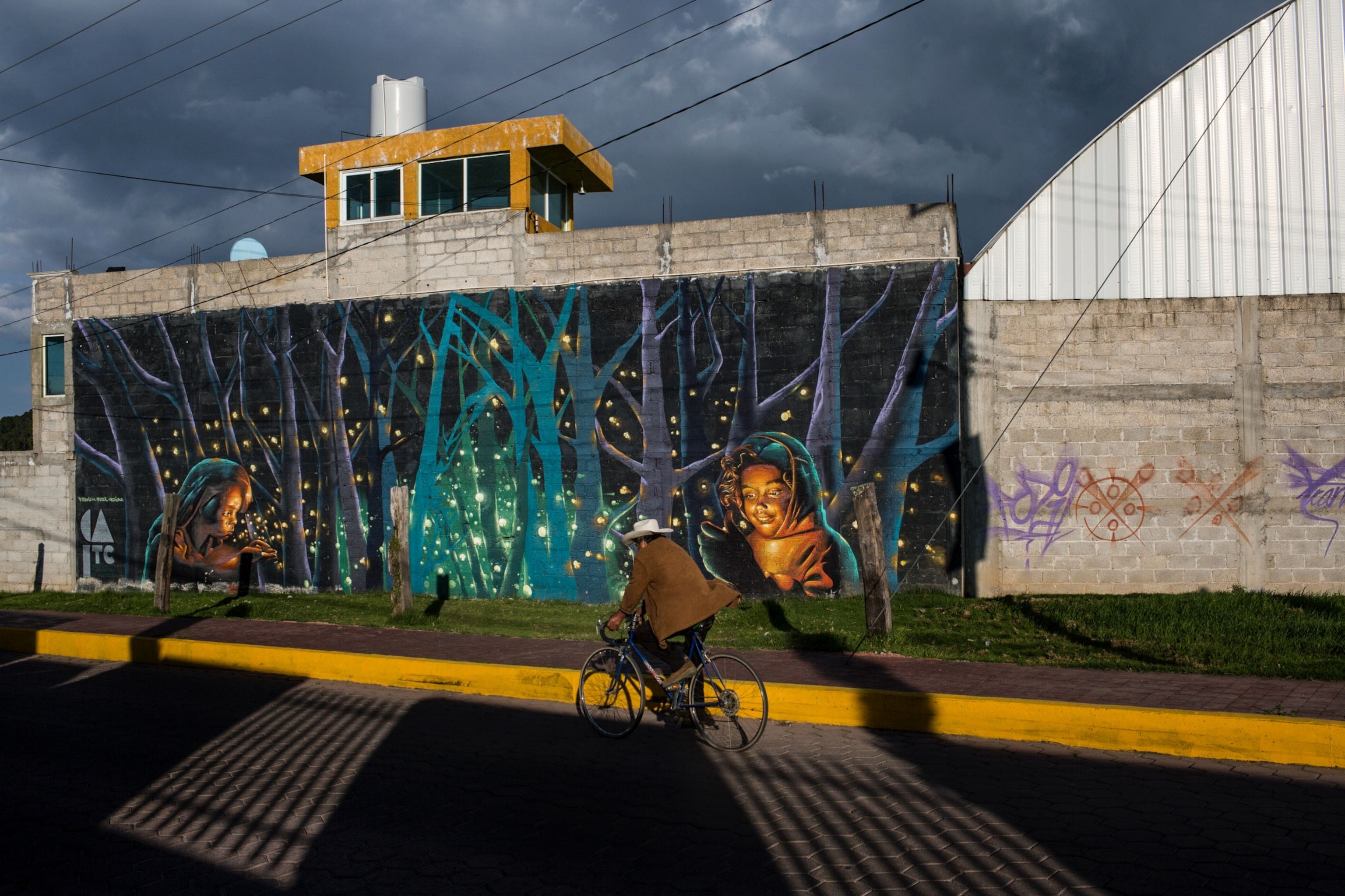 a man riding his bike past a mural