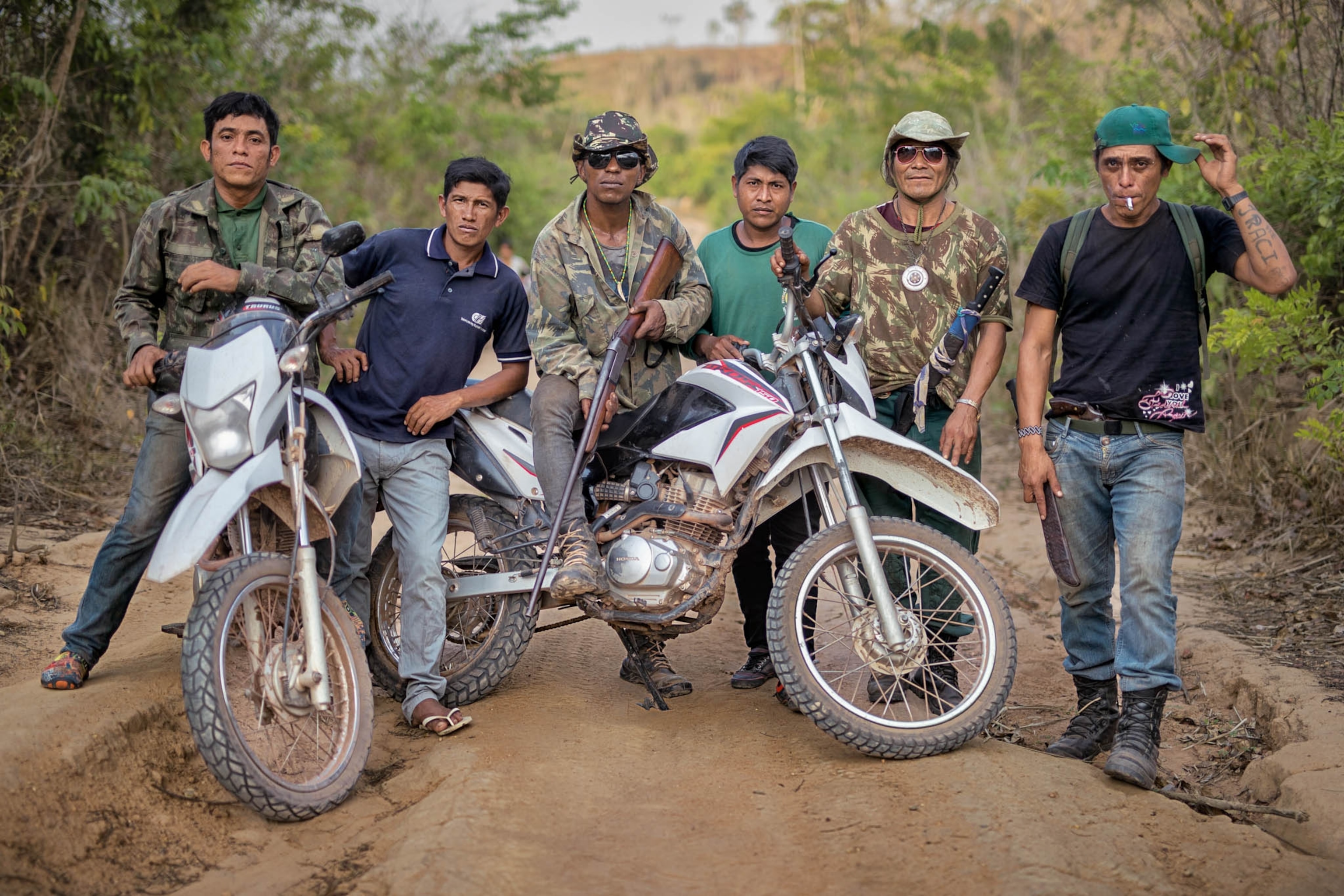 six men with motorcycles standing for a portrait outside