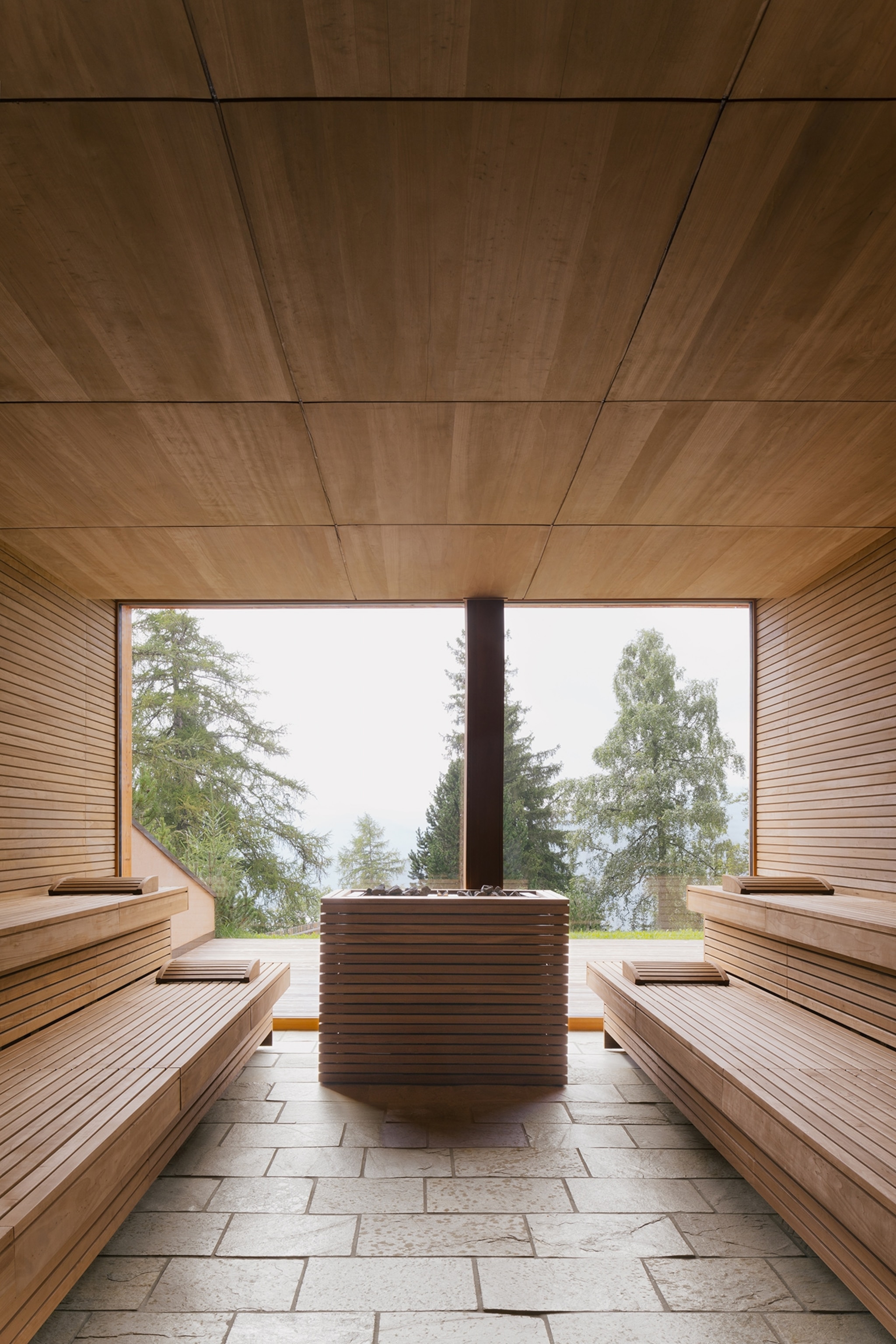 Wooden panels on the wall of and a deep tub facing large glass windows.