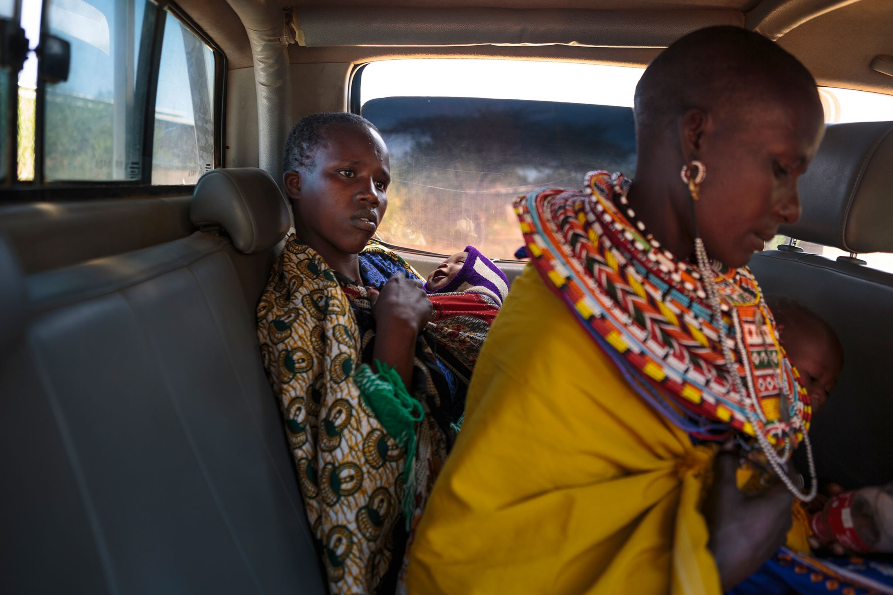 two young women from the oldinyiro village in kenya hold their babies in the back of a truck as they go to safe house to protect their infants from death