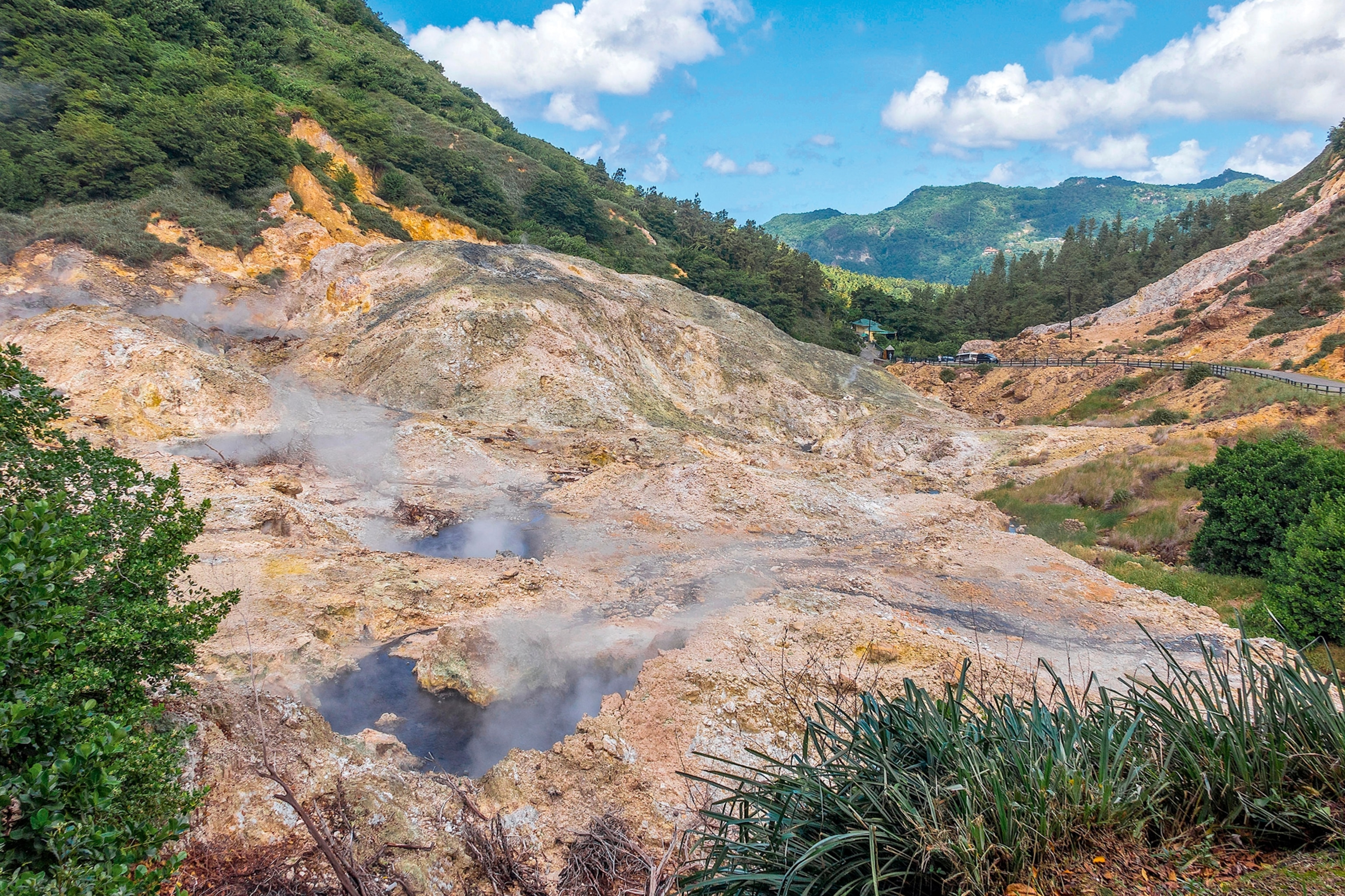 Steaming natural hot springs in a rocky, mountainous landscape.