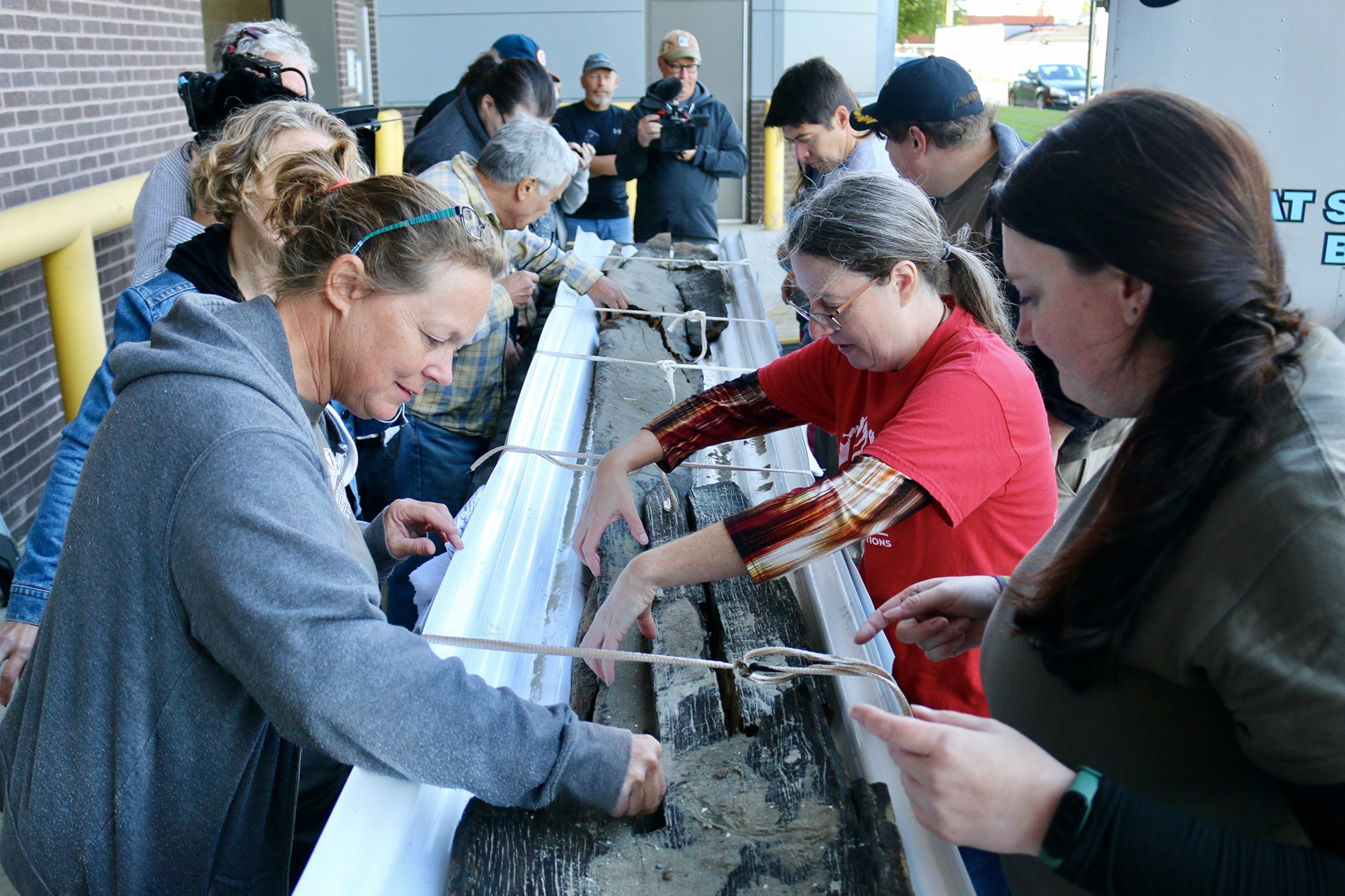 People flank the sides of the bits of canoe.