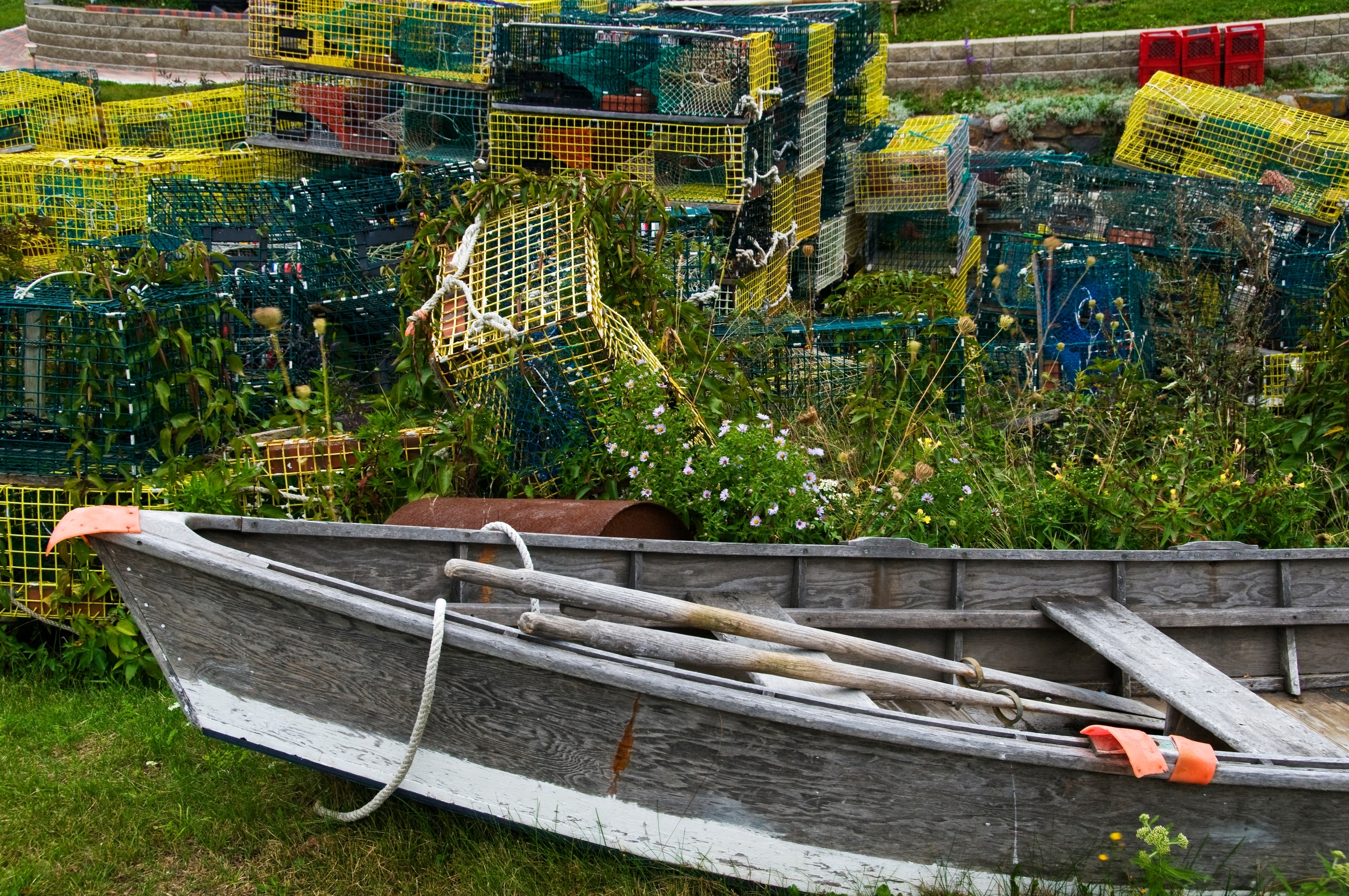 Boat sitting on the ground in front of colorful lobster pots on Monhegan Island, Maine