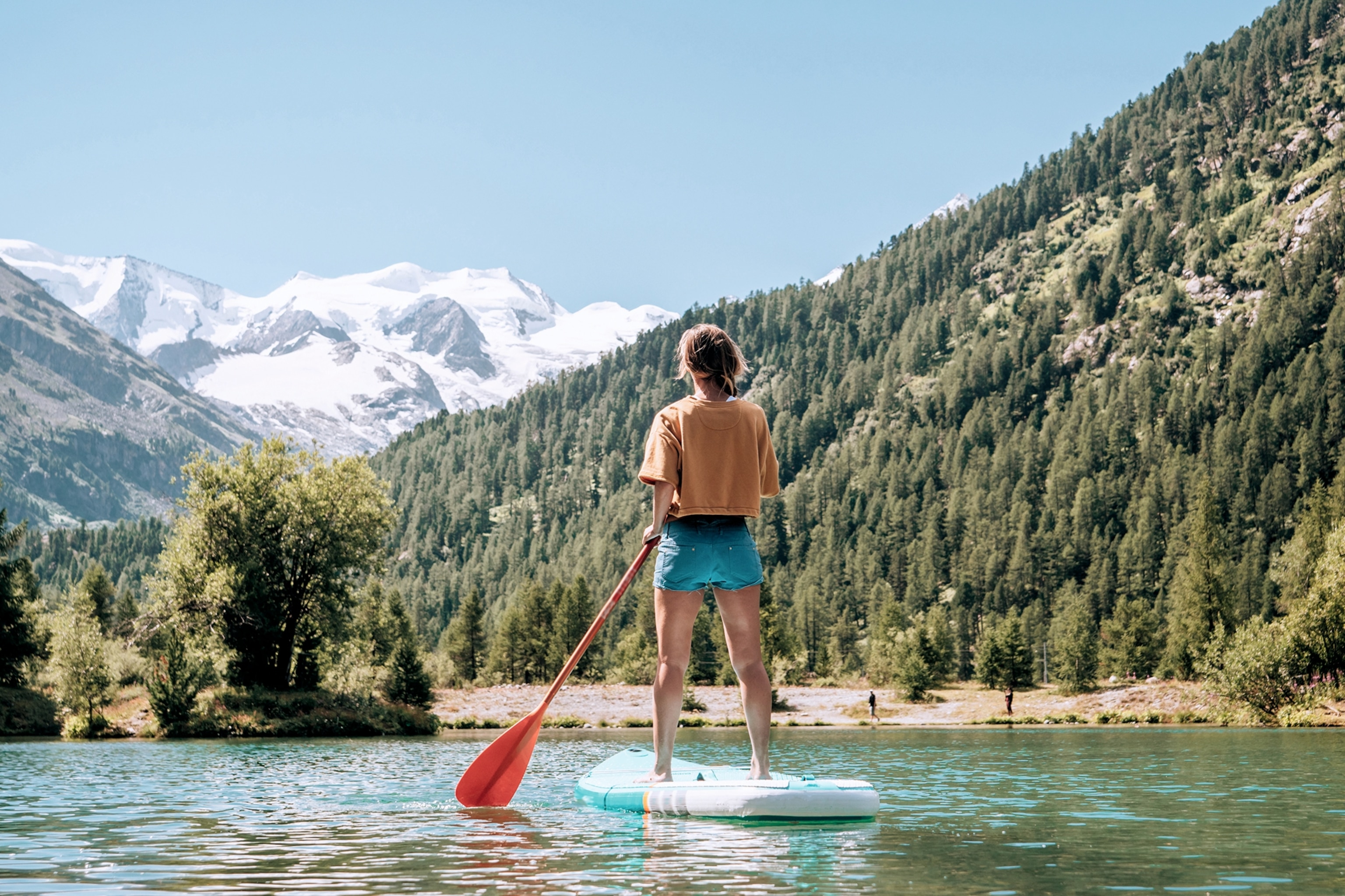 Person on a stand-up paddleboard on an Alpine lake.