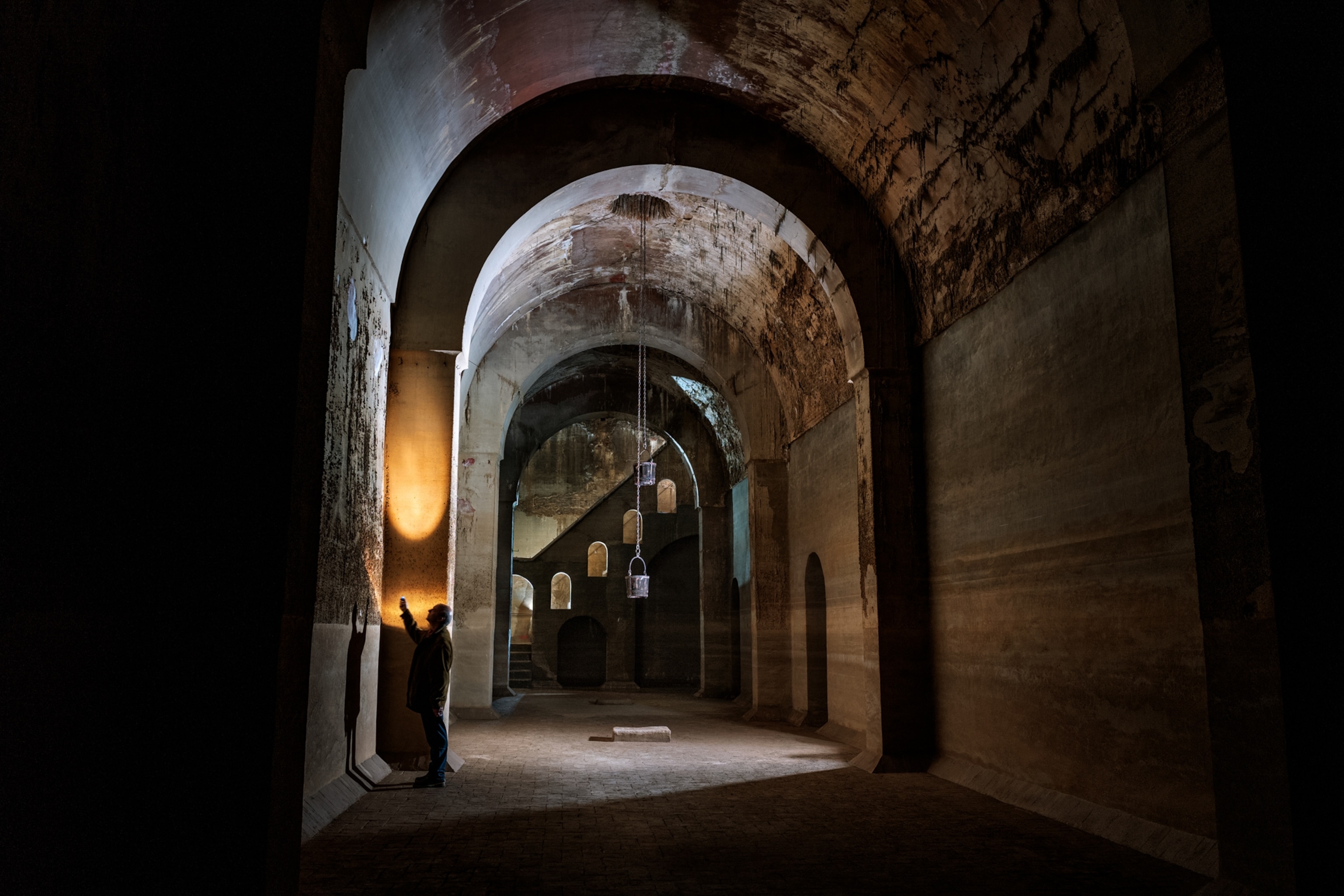 Man in the long passway with arched ceiling.