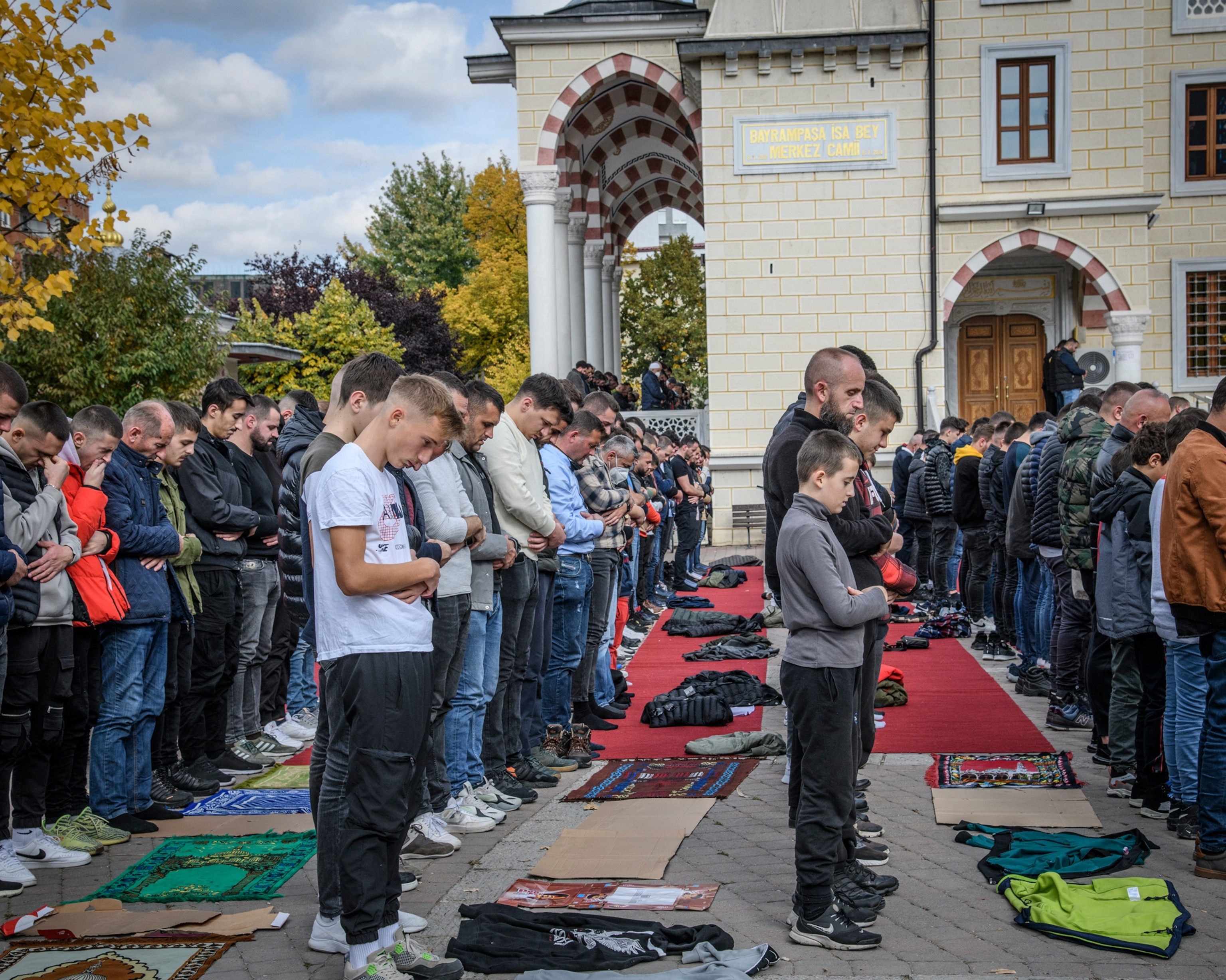 Picture of a group standing in rows with their heads bowed and praying.