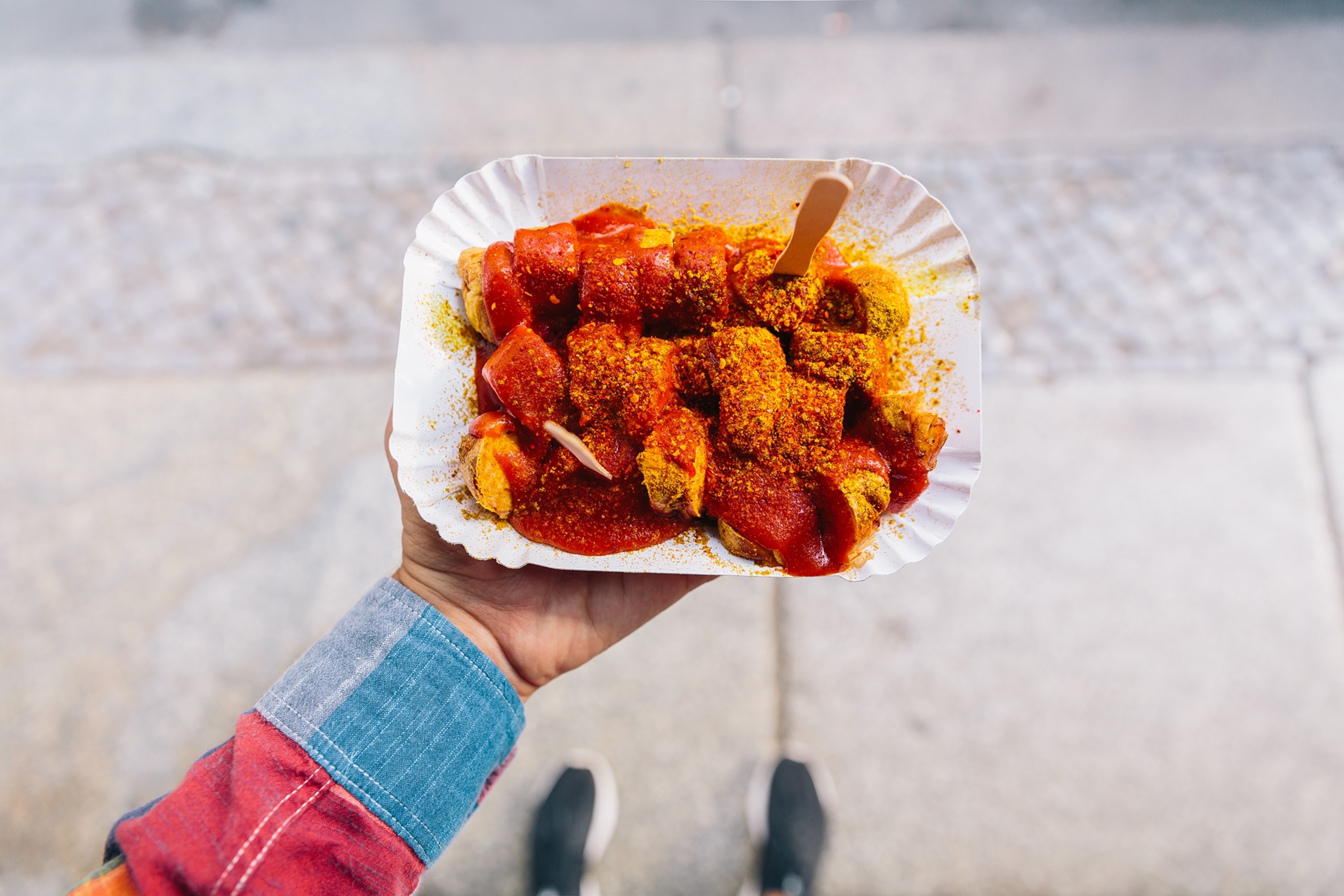 a hand holding currywurst