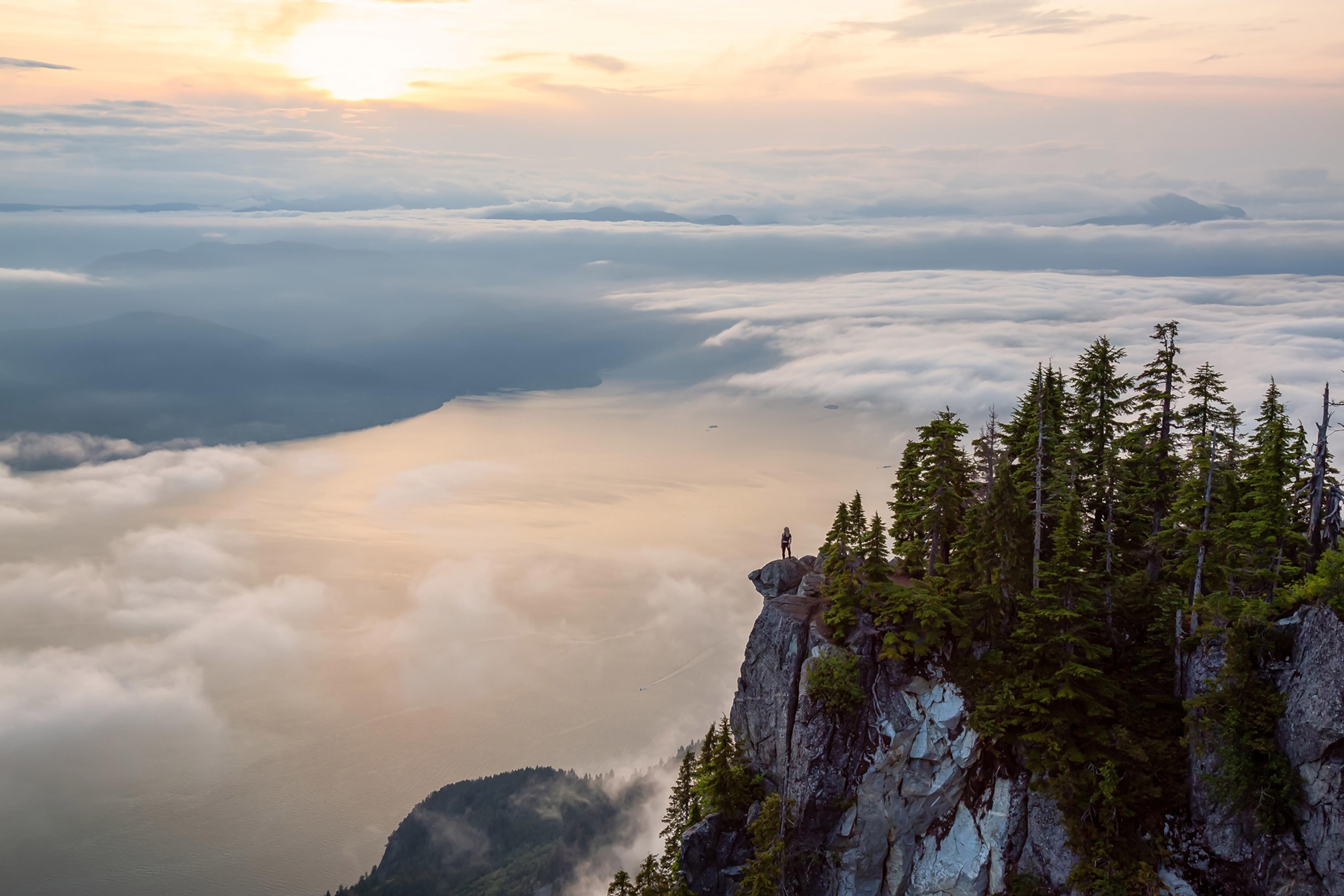 a hiker on top of a mountain covered in clouds in British Columbia