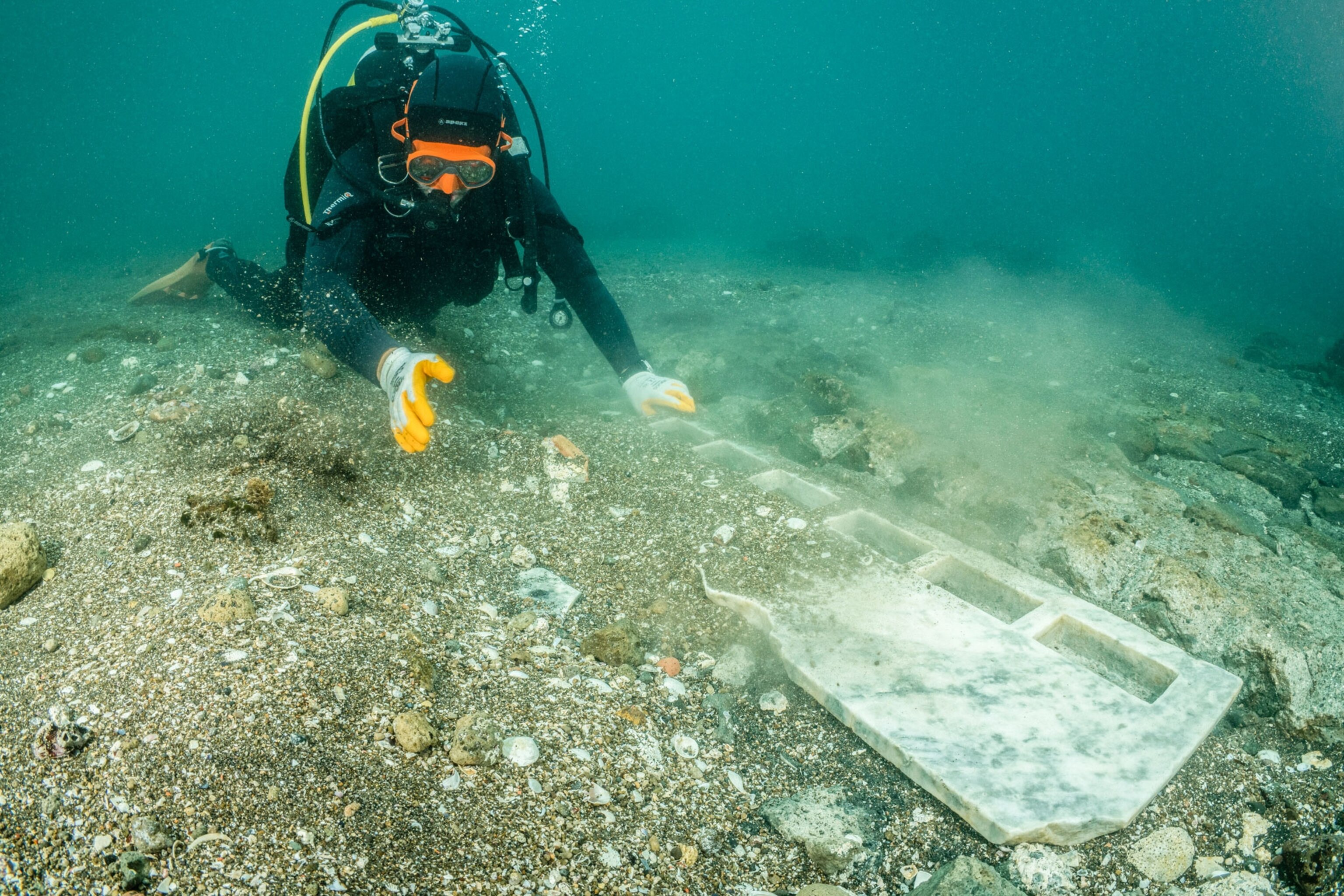 Diver on the ocean floor inspects an white marble altar from a ancient Nabataeans temple.