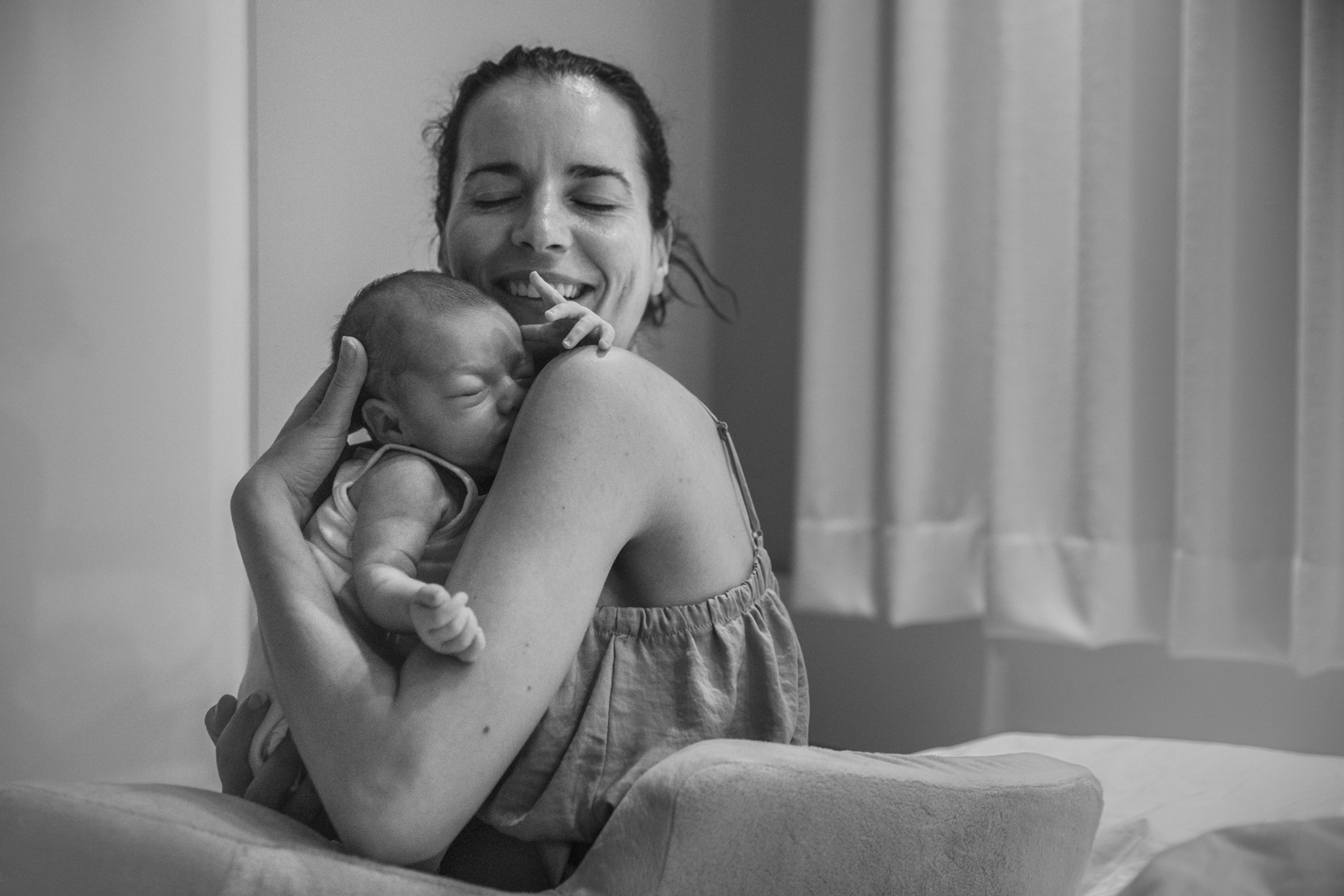 Mother holding baby to her heart and smiling with closed eyes.