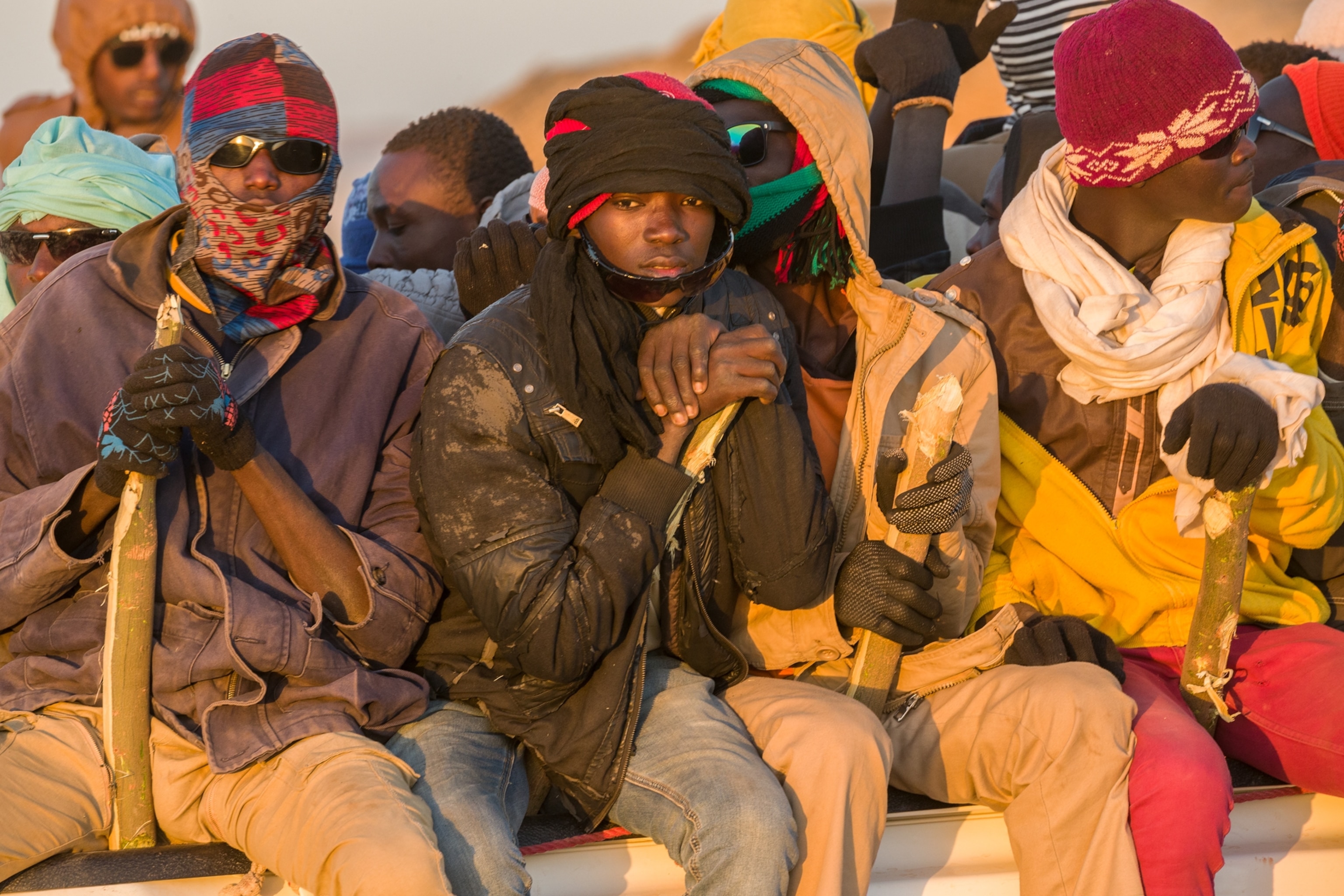 young men on a truck holding sticks for balance wearing winter clothes