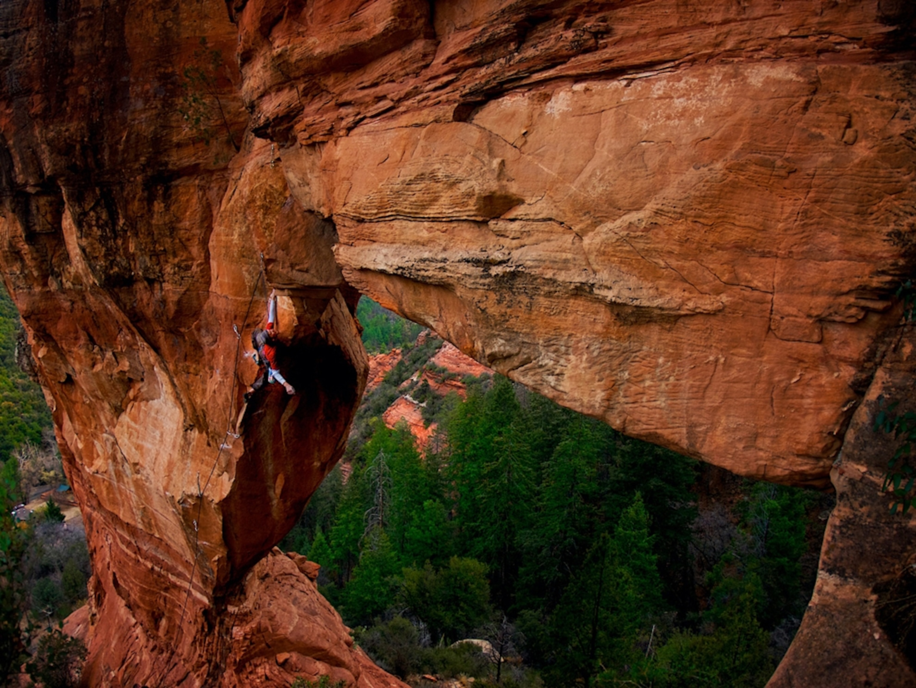 Climber dangling from red rock