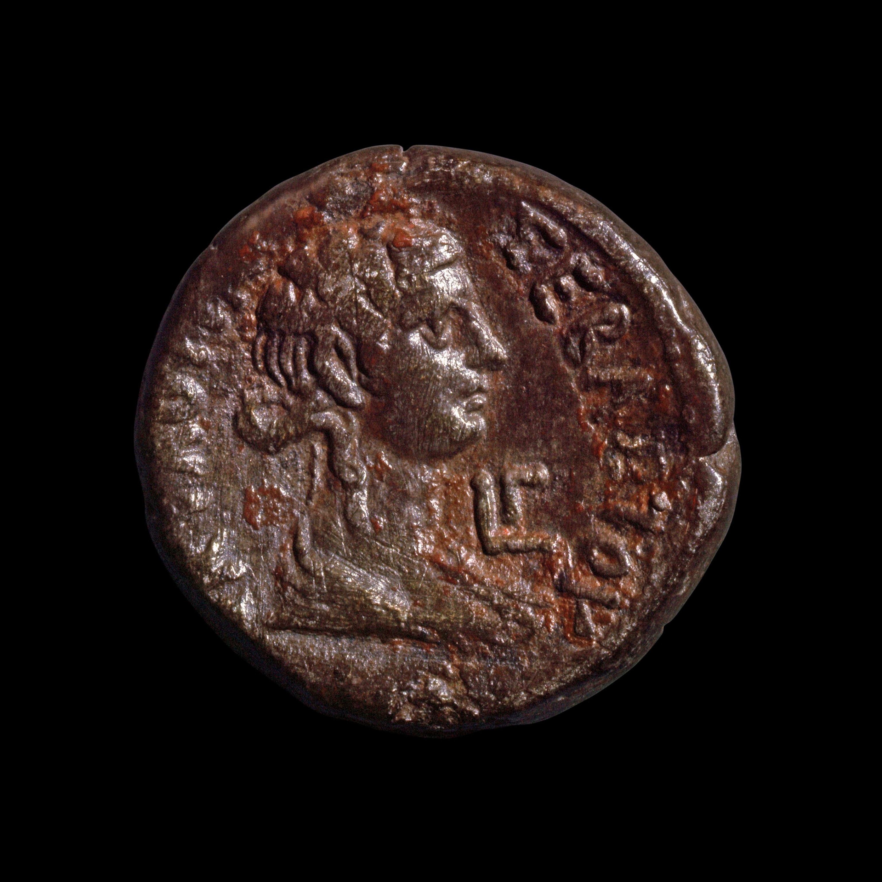 The side profile of a woman on an old bronze coin