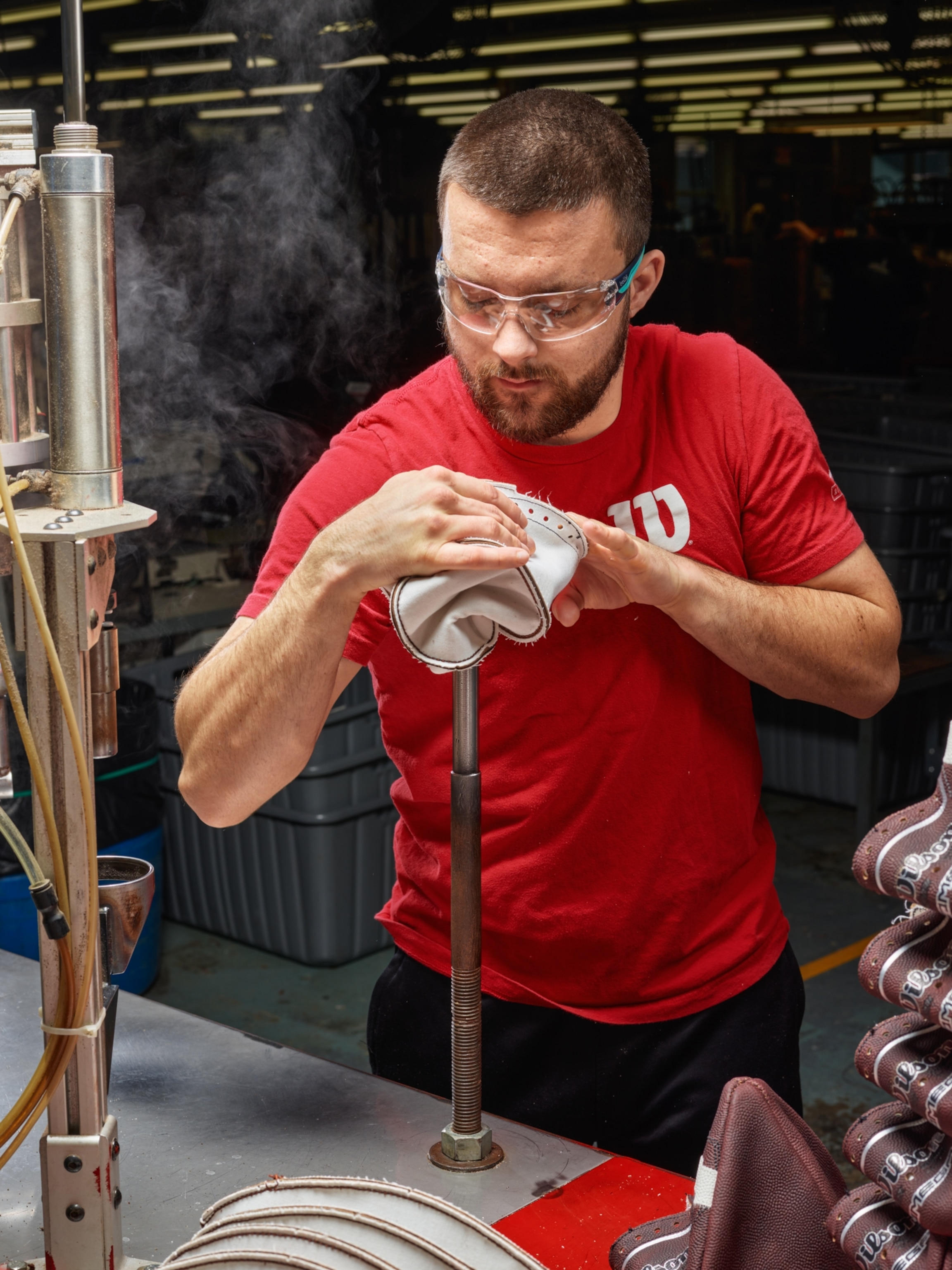 A factory worker turning a football right side out.