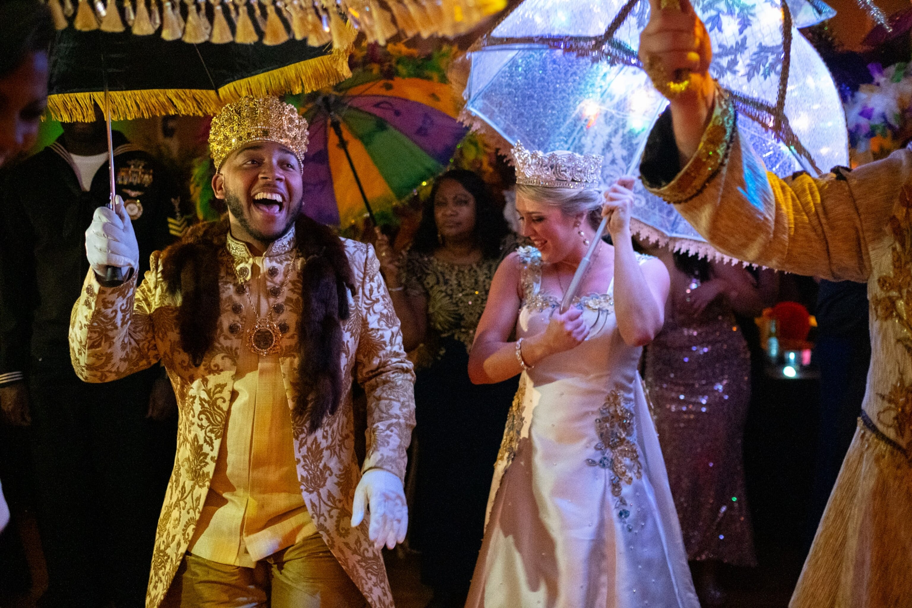 two people dressed in colorful formal attire dancing holding umbrellas