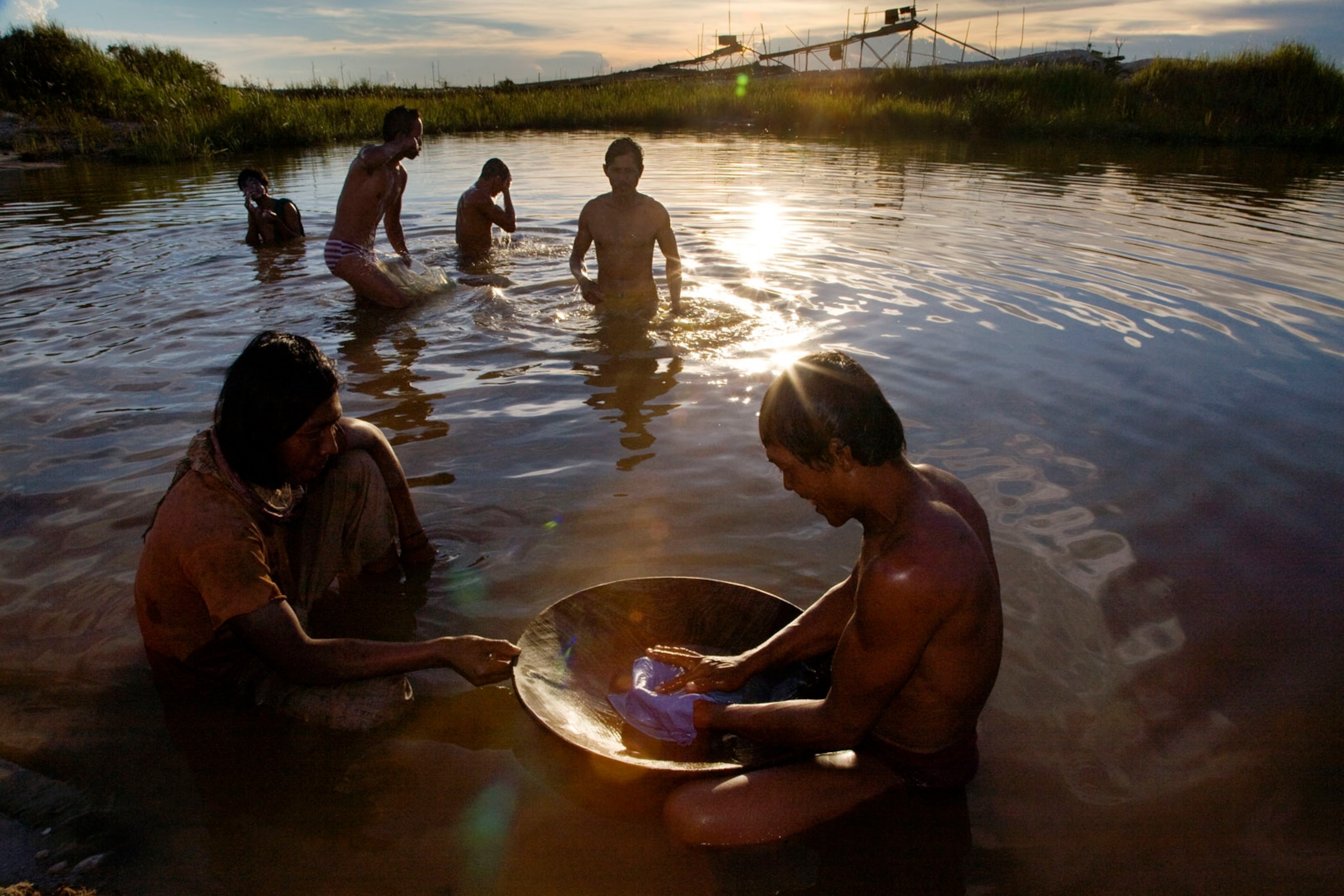 Kalimantan miners in a pond mixing mercury with ore to separate out the gold