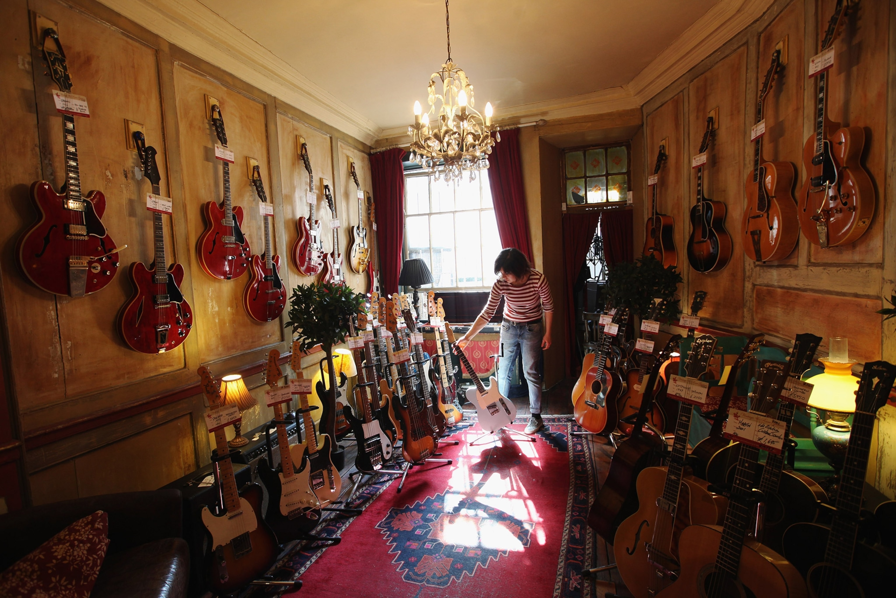 An employee sorts a display of guitars in a shop on Denmark Street