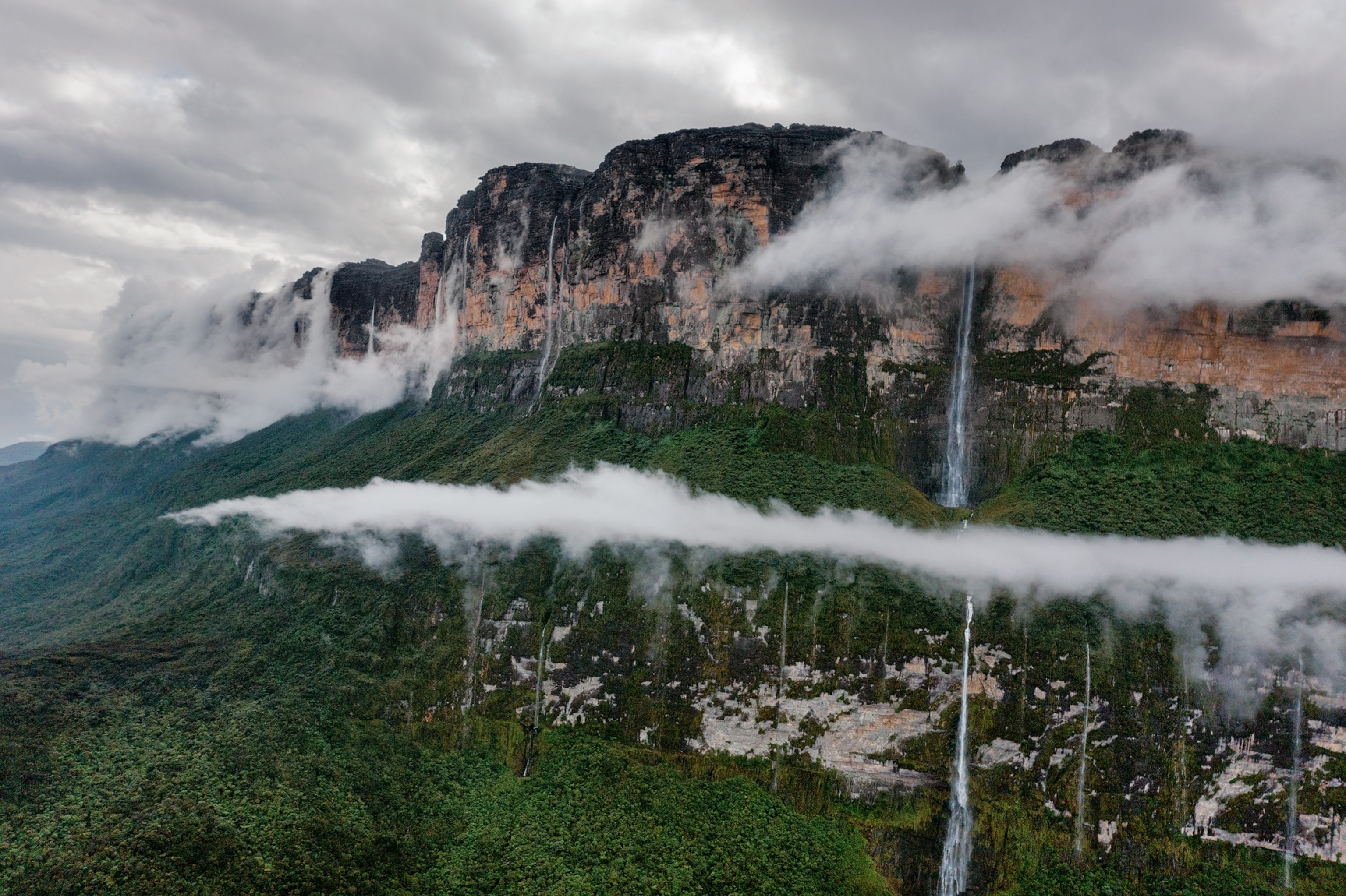 Picture of mountain with flat top, waterfalls and clouds.
