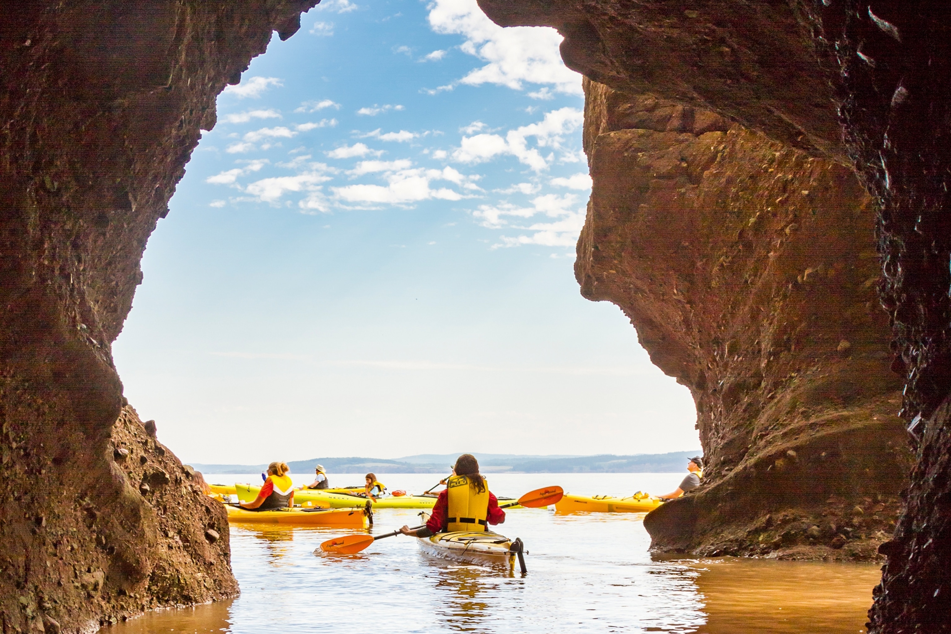 People kayaking through a hole in Hopewell Rocks, in the Bay of Fundy.