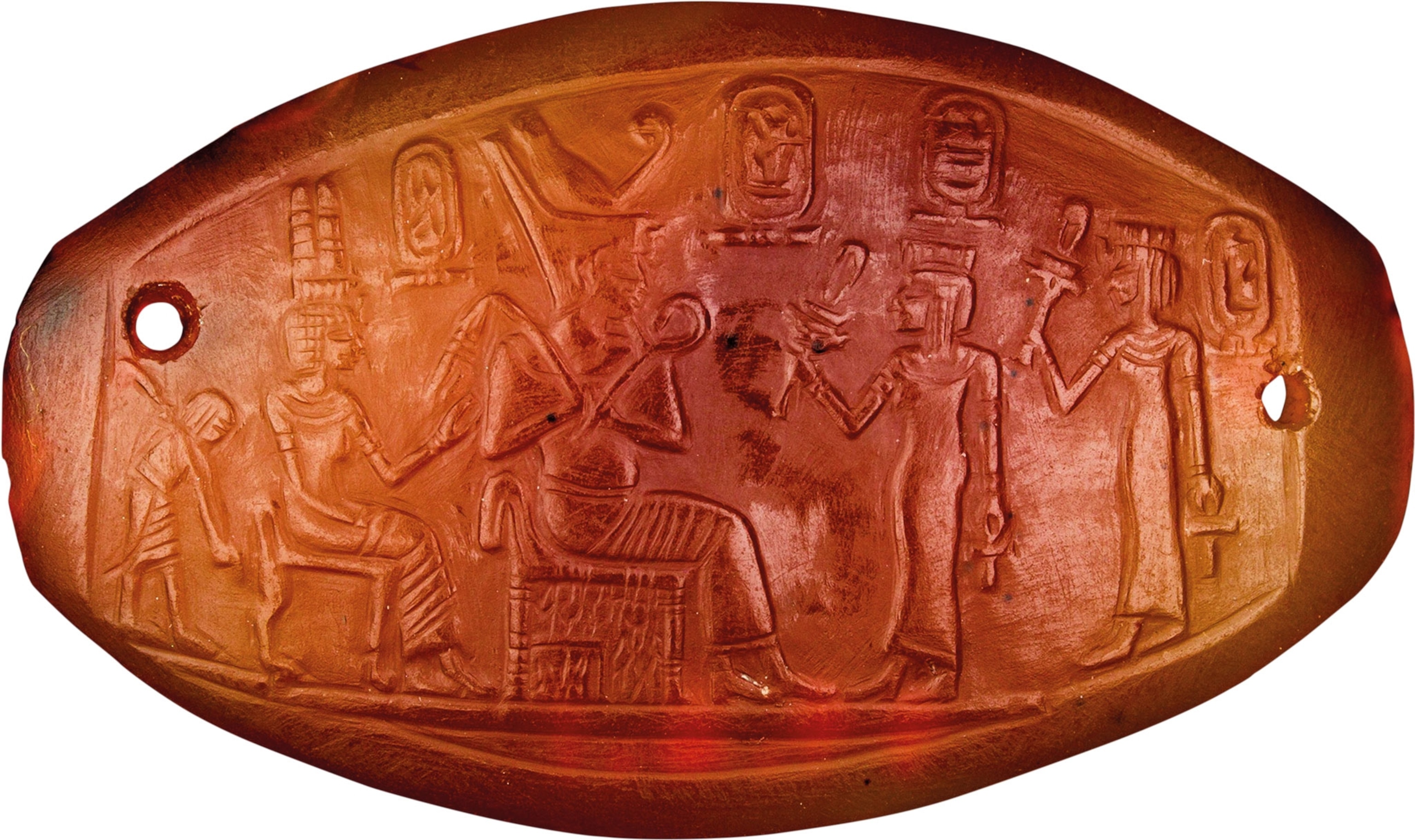 An amber colored plaque with a carving on it