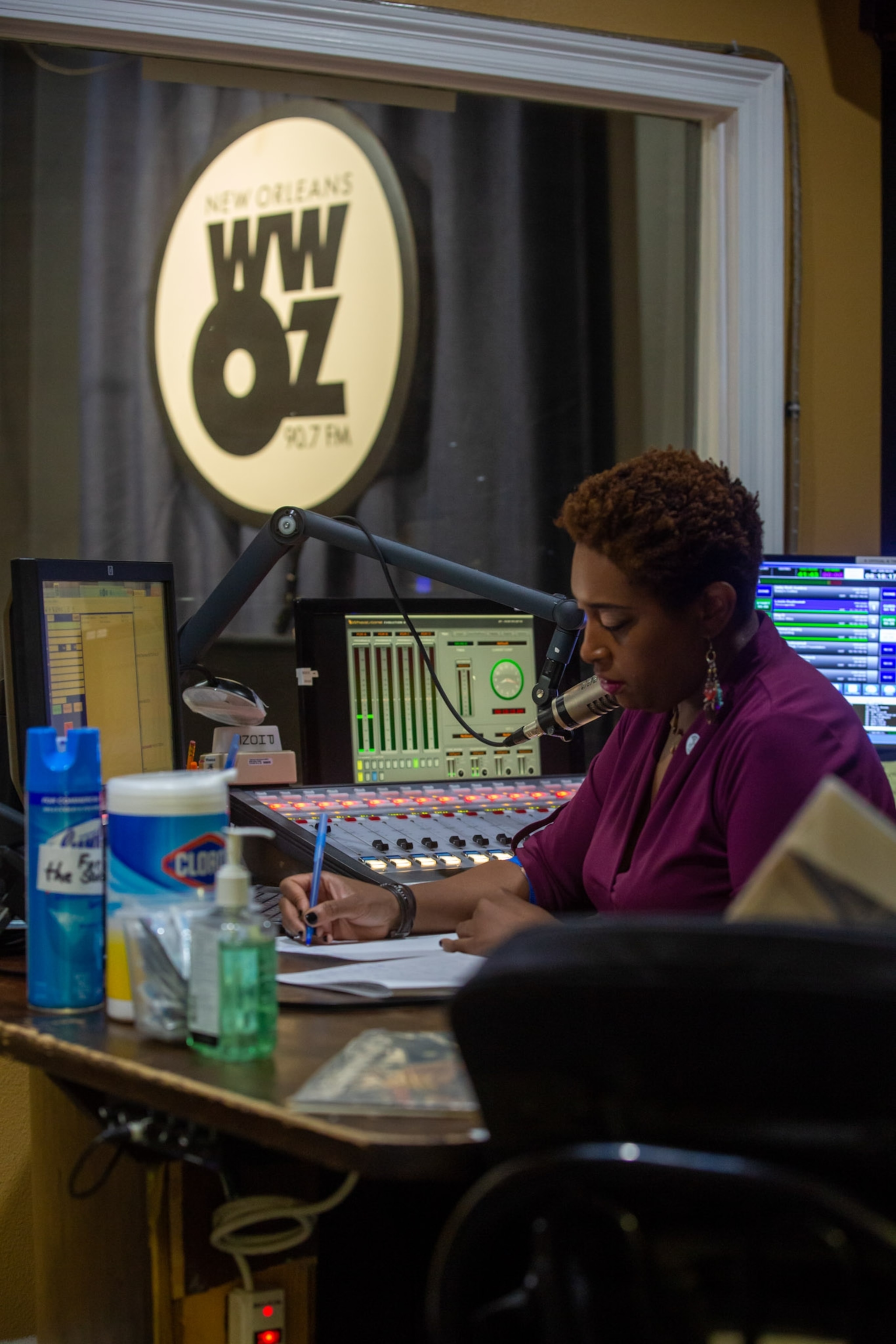 a woman inside of a radio recording station, writing on a notepad
