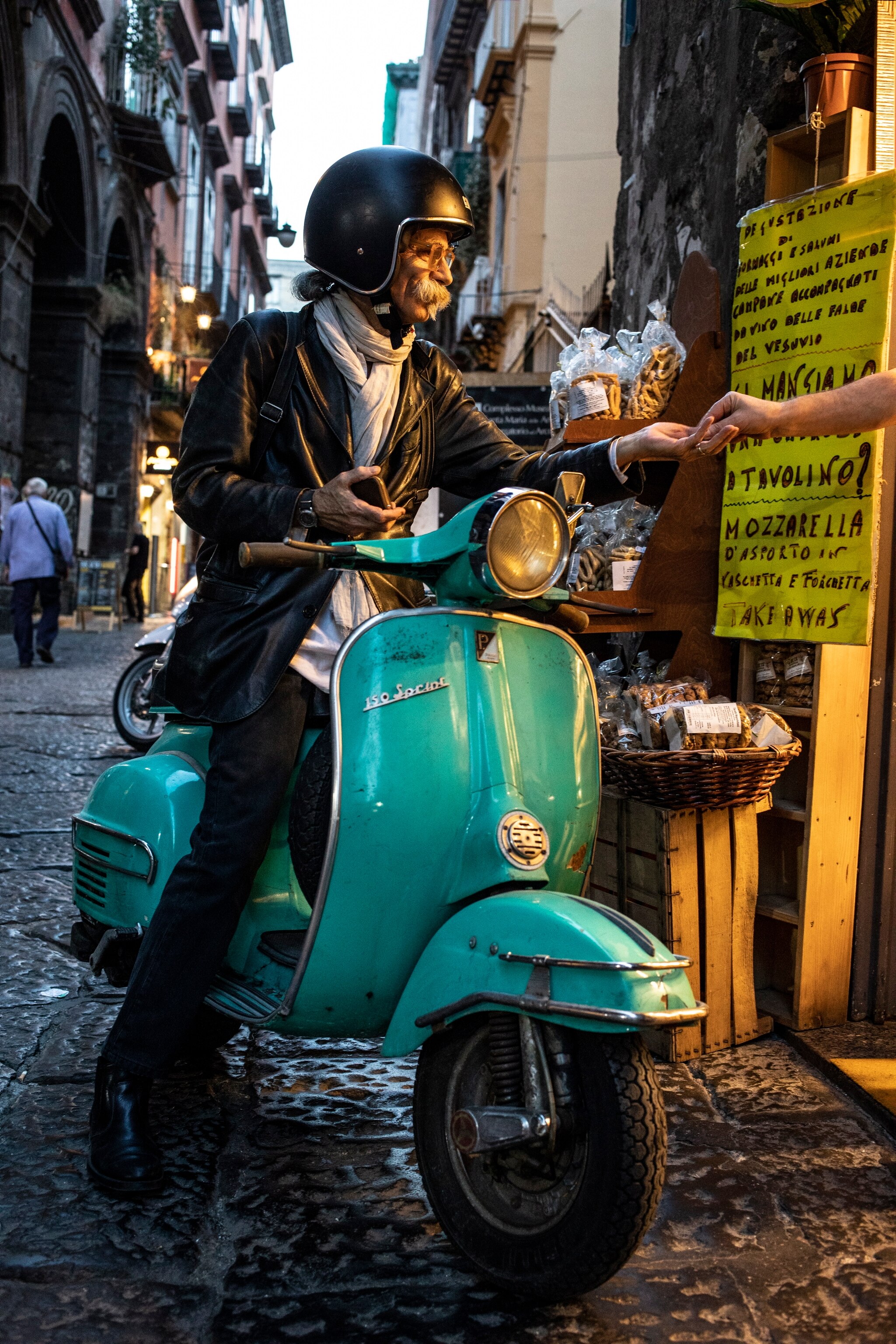 a man on a vespa motorbike pulls up next to a store